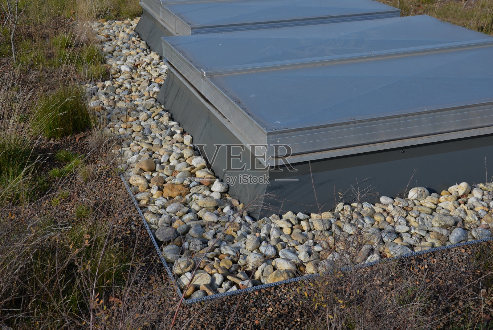 金属格栅和屋顶花园的一个舱口。覆盖在冷却装置后部入口的金属片和金属。门周围的区域覆盖着鹅卵石。防火边缘照片摄影图片