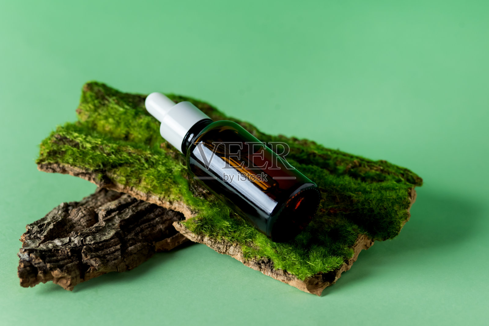 用移液管玻璃瓶的血清在树皮、树、苔藓和草的有机化妆品在绿色背景上环境清晰的自然化妆品照片摄影图片