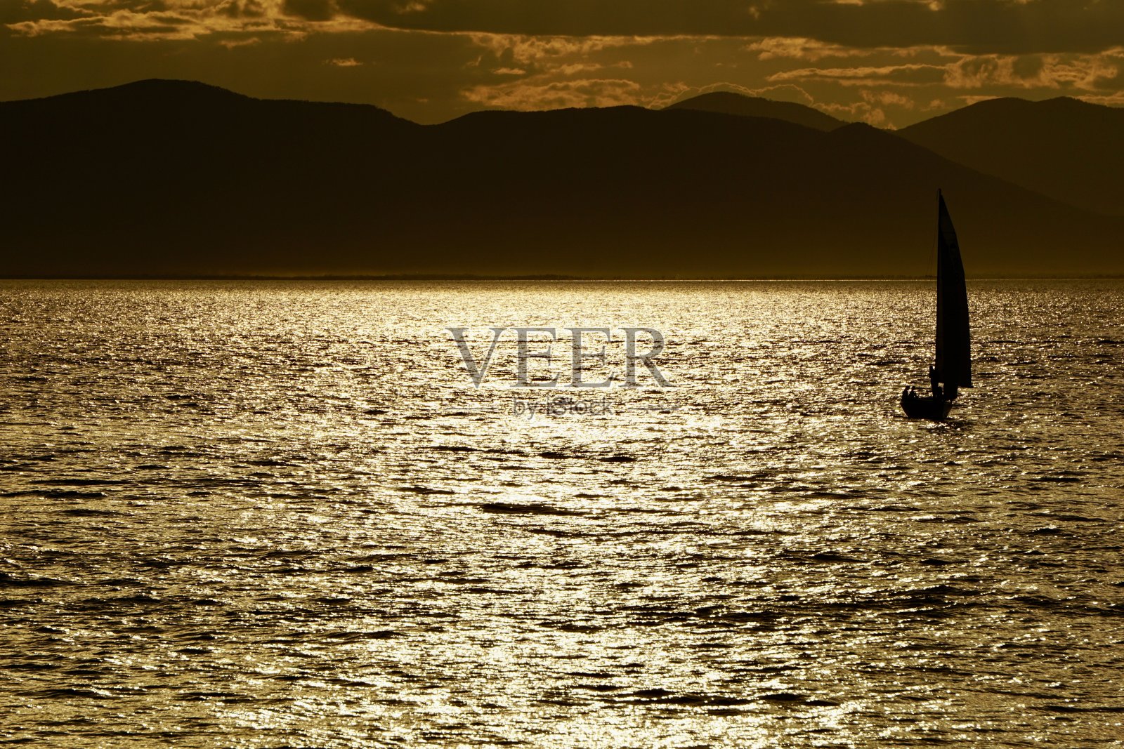 日落时的游艇。海参崴美丽的日落。日本海海滩上的日落。游艇在日落时在海上航行。海上日落,高山和游艇。照片摄影图片