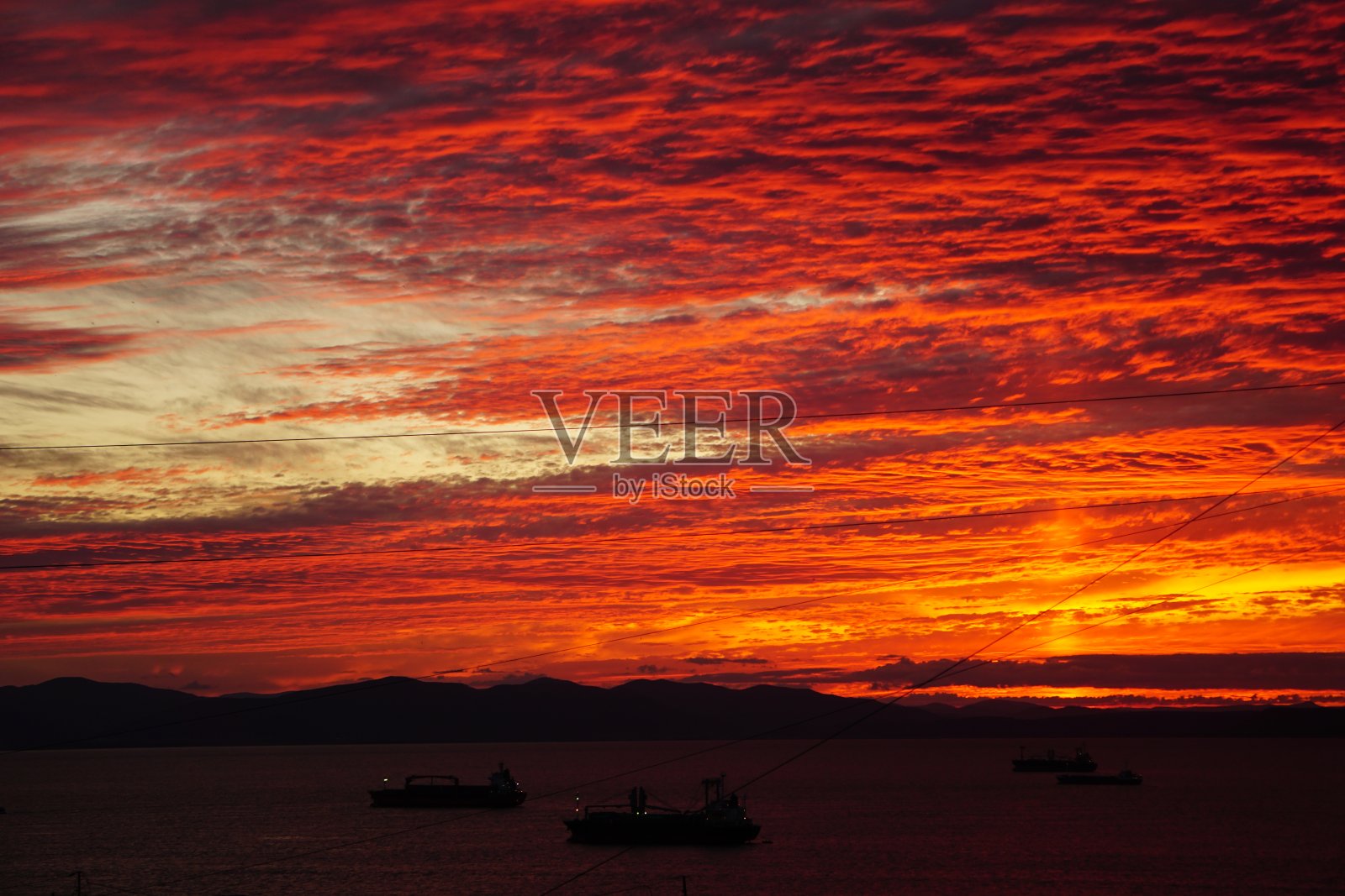 海上灿烂的日落。海上红褐色的日落。红色日落时海上最明亮的天空。红色的日落倒映在海面上。红色夕阳下的船只。照片摄影图片