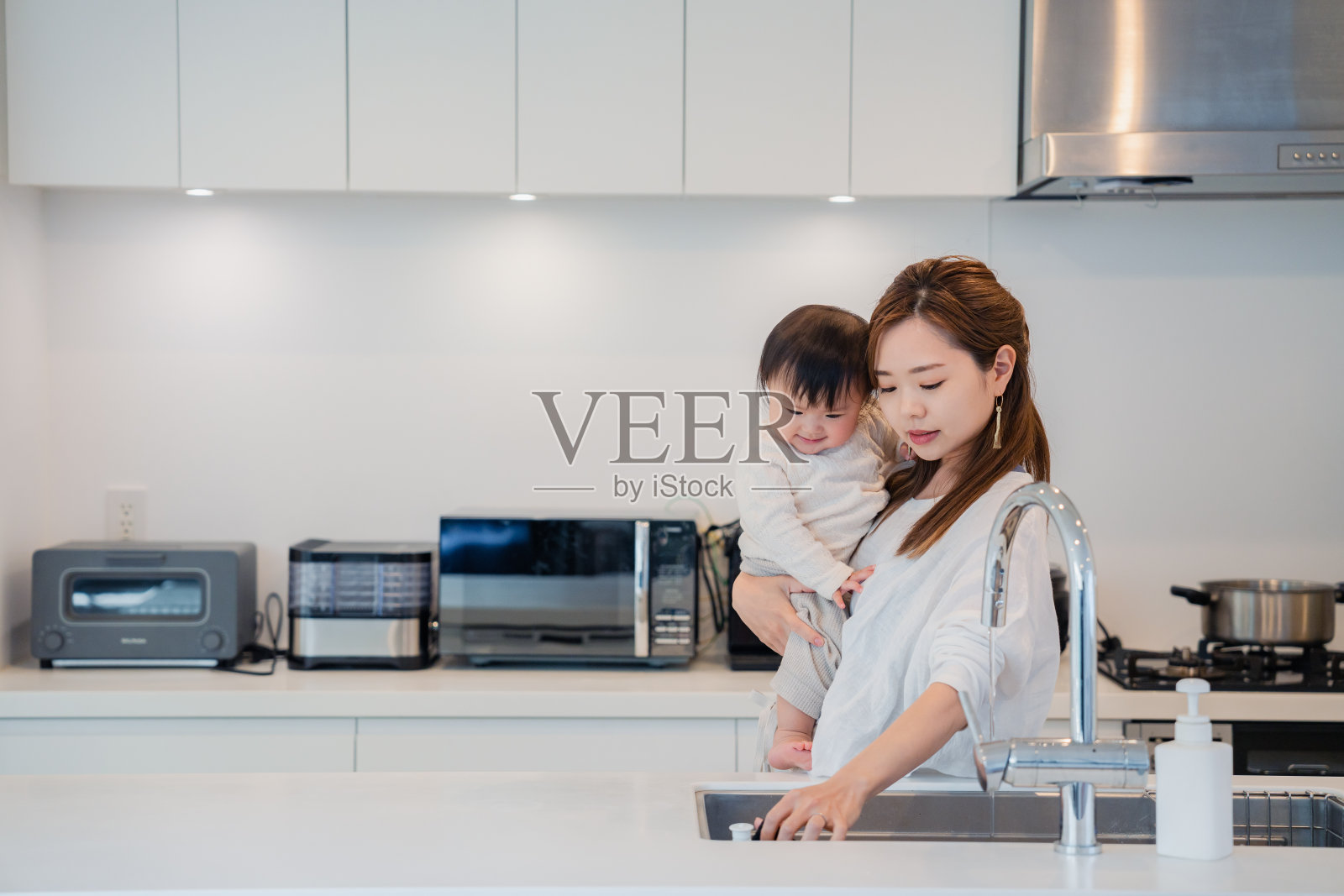 母亲一边抱着孩子一边做家务照片摄影图片