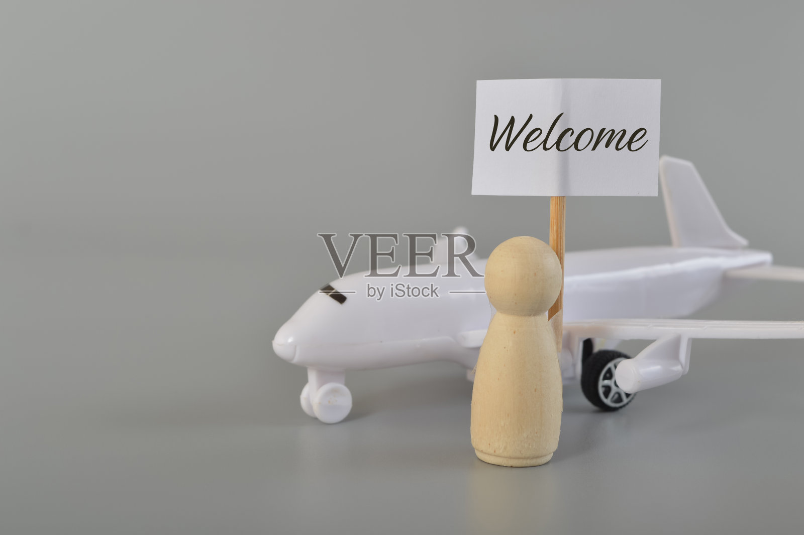 飞机和木制玩偶玩偶的标牌上写着欢迎。飞机商务旅行的概念。照片摄影图片