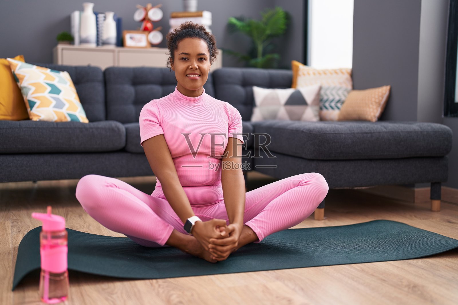 一名非洲裔美国妇女自信地微笑着在家里伸展双腿照片摄影图片