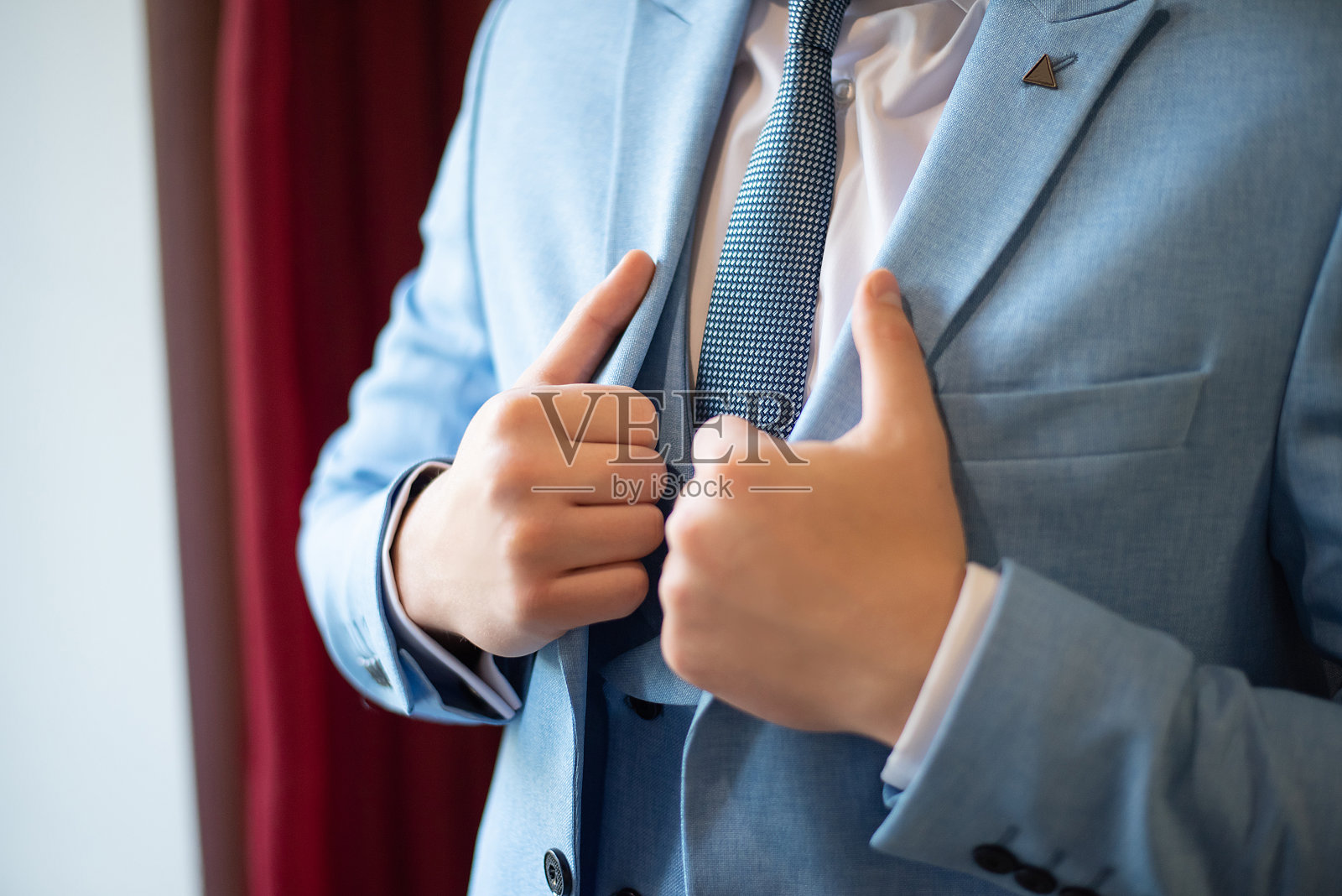 新郎在婚礼前的准备工作。领带和夹克。手的特写照片摄影图片