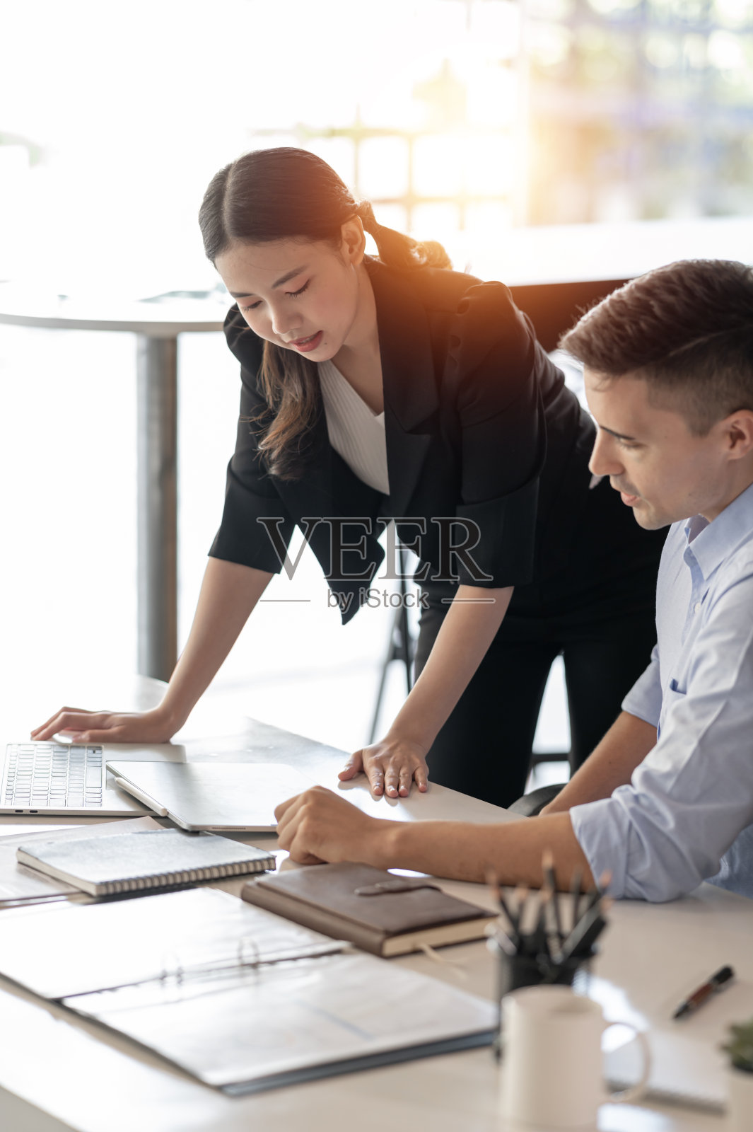 两个年轻的商务人士在办公室用平板电脑讨论和开会。照片摄影图片