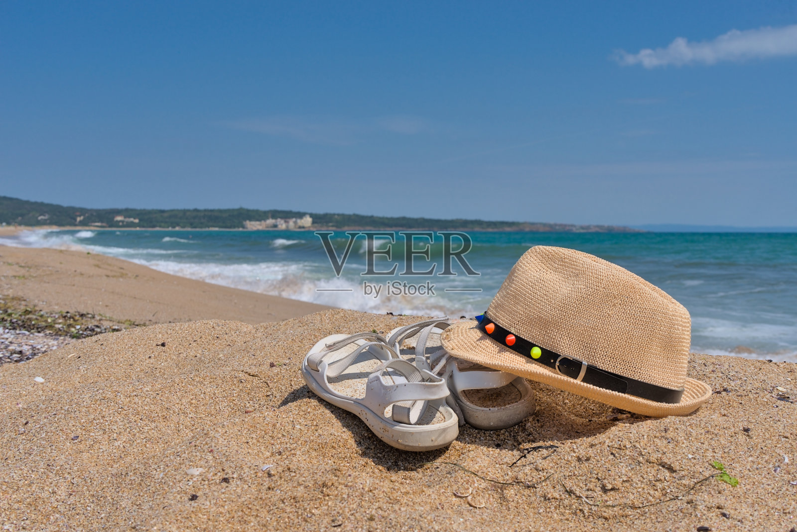 白色的夏季凉鞋和草帽在沙滩上,背景是大海和海滩照片摄影图片