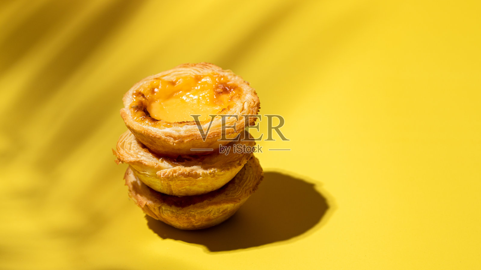 在黄色的背景上加上硬光和阴影的蛋挞酥。现代甜蜜的形象,照片摄影图片