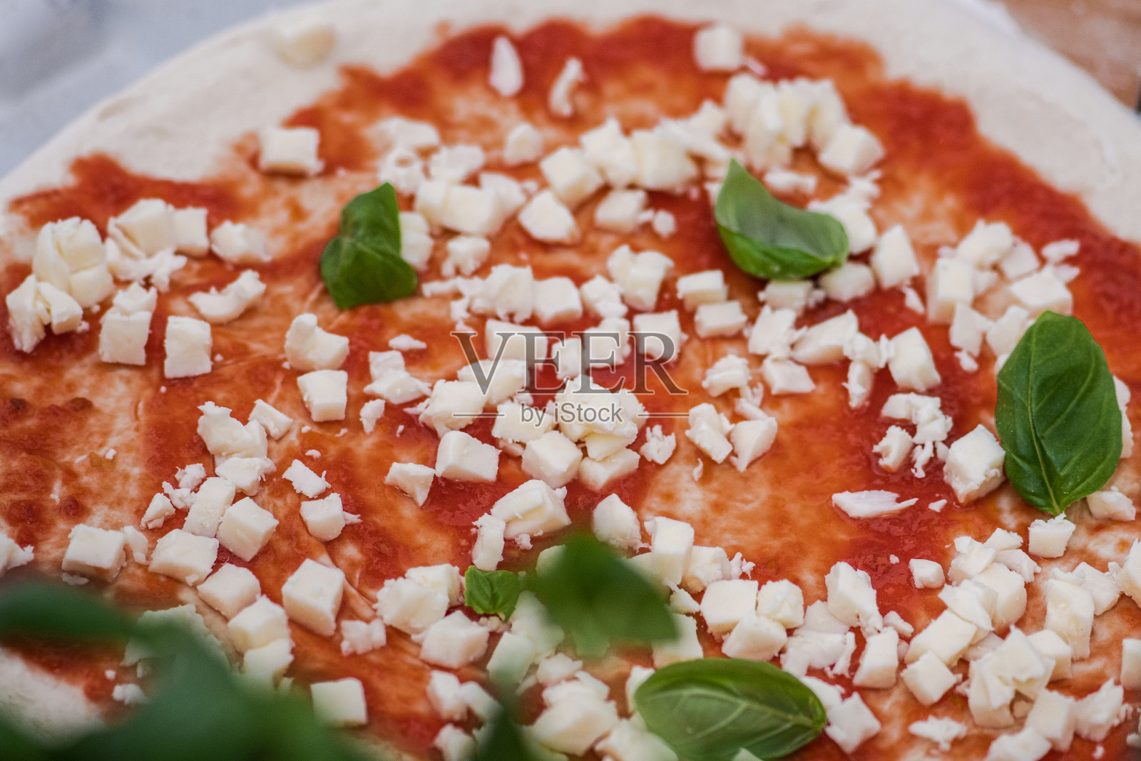 准备披萨配番茄酱,新鲜马苏里拉奶酪和绿色罗勒叶照片摄影图片