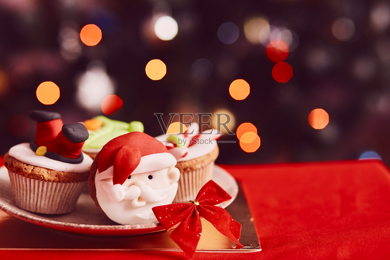 唯美惬意的圣诞茶时间。bokeh圣诞树前的装饰纸杯蛋糕。节日心情好。有选择性的重点。照片摄影图片