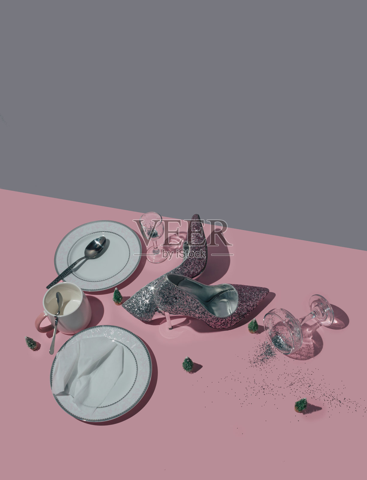 新年庆祝用的桌子,鞋,盘子和玻璃在粉红色和灰色的背景。最小的概念。照片摄影图片