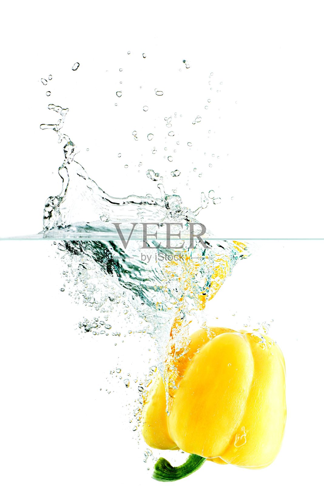 黄色的甜椒落入水中,溅起白色的水花照片摄影图片