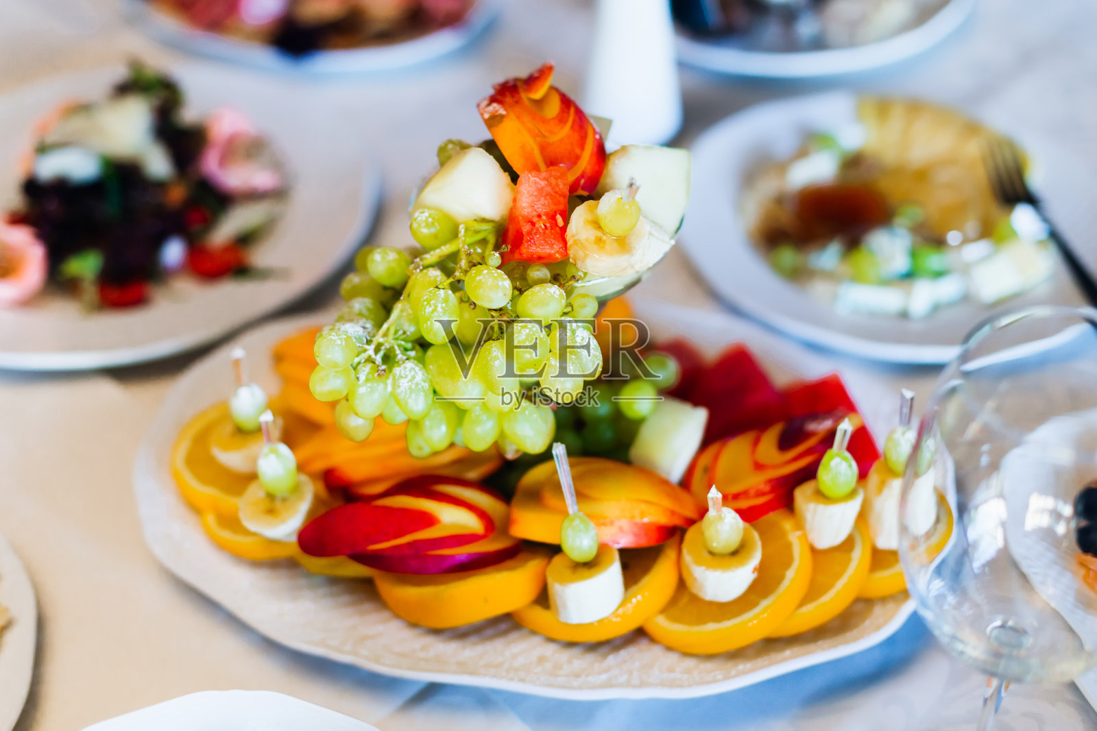 装饰精美的水果片放在婚礼桌上的白色盘子上照片摄影图片