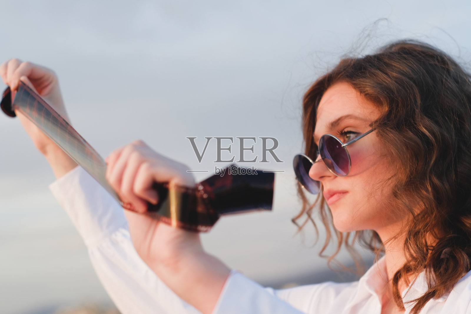 在一个阳光明媚的日子里,年轻的潮人手里拿着胶卷照片摄影图片