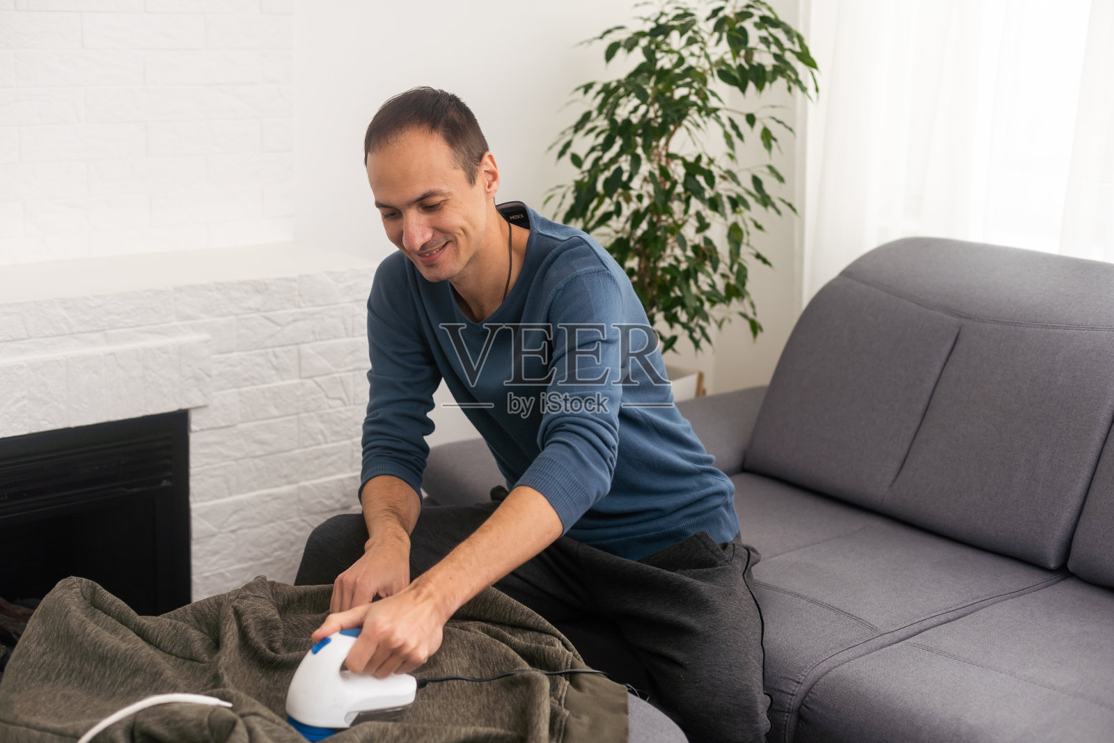 一名男子用刮毛刀去除织物上的小药丸。照片摄影图片