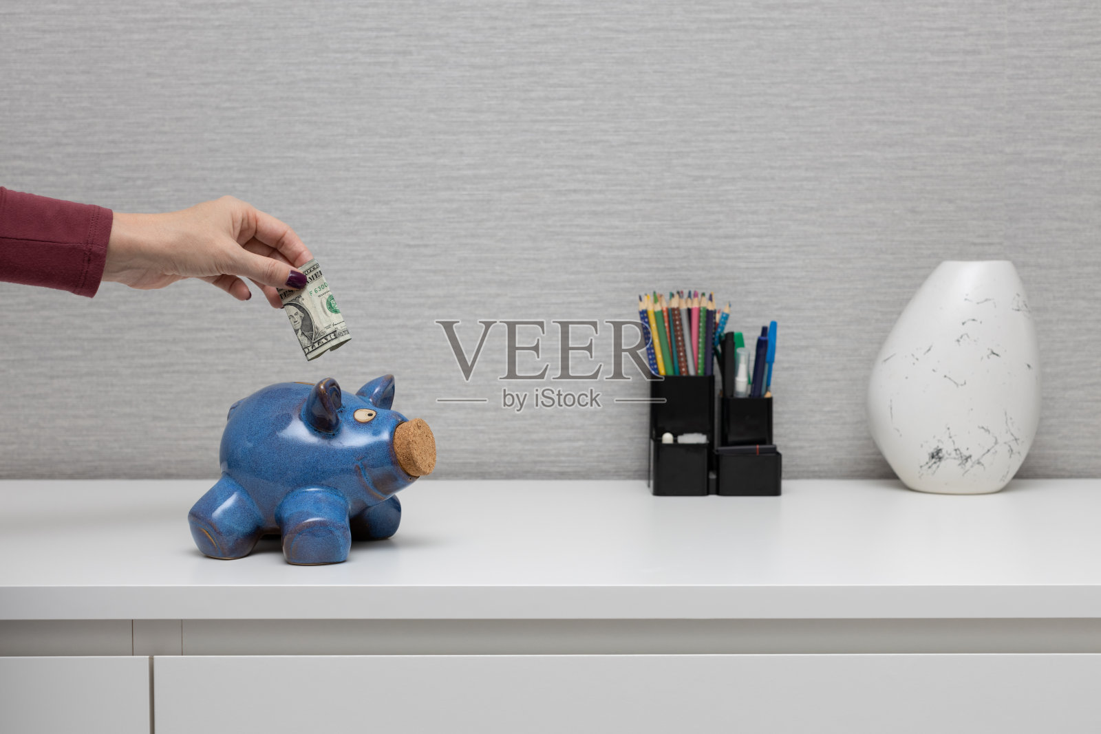 男人把钱放进存钱罐里。汉德把钱放进存钱罐里。照片摄影图片