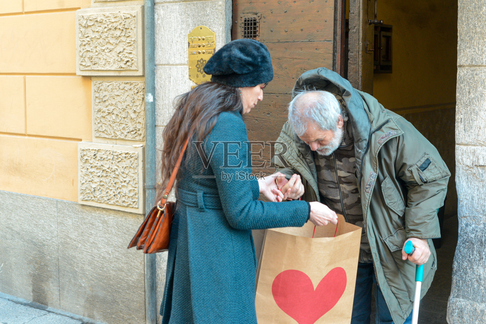 特写的老人看着纸袋由一个穿绿色外套的女人。照片摄影图片