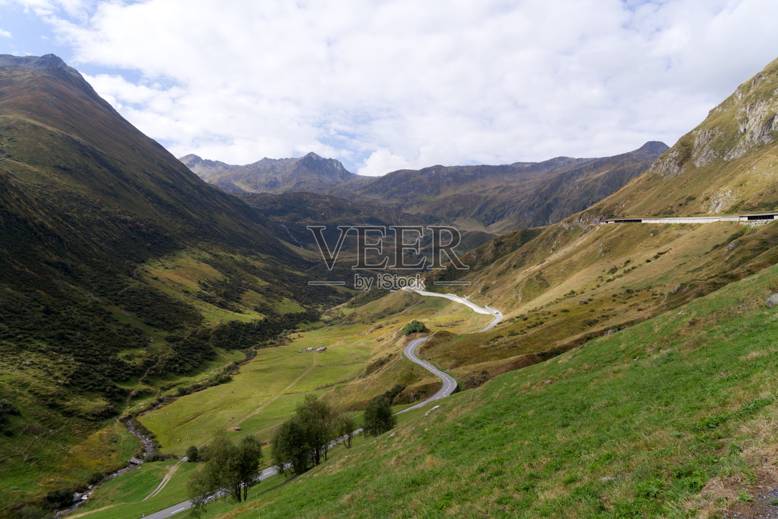 在一个阳光明媚的夏末早晨,瑞士山口奥伯拉帕斯的山峰和蜿蜒的道路全景。照片摄影图片