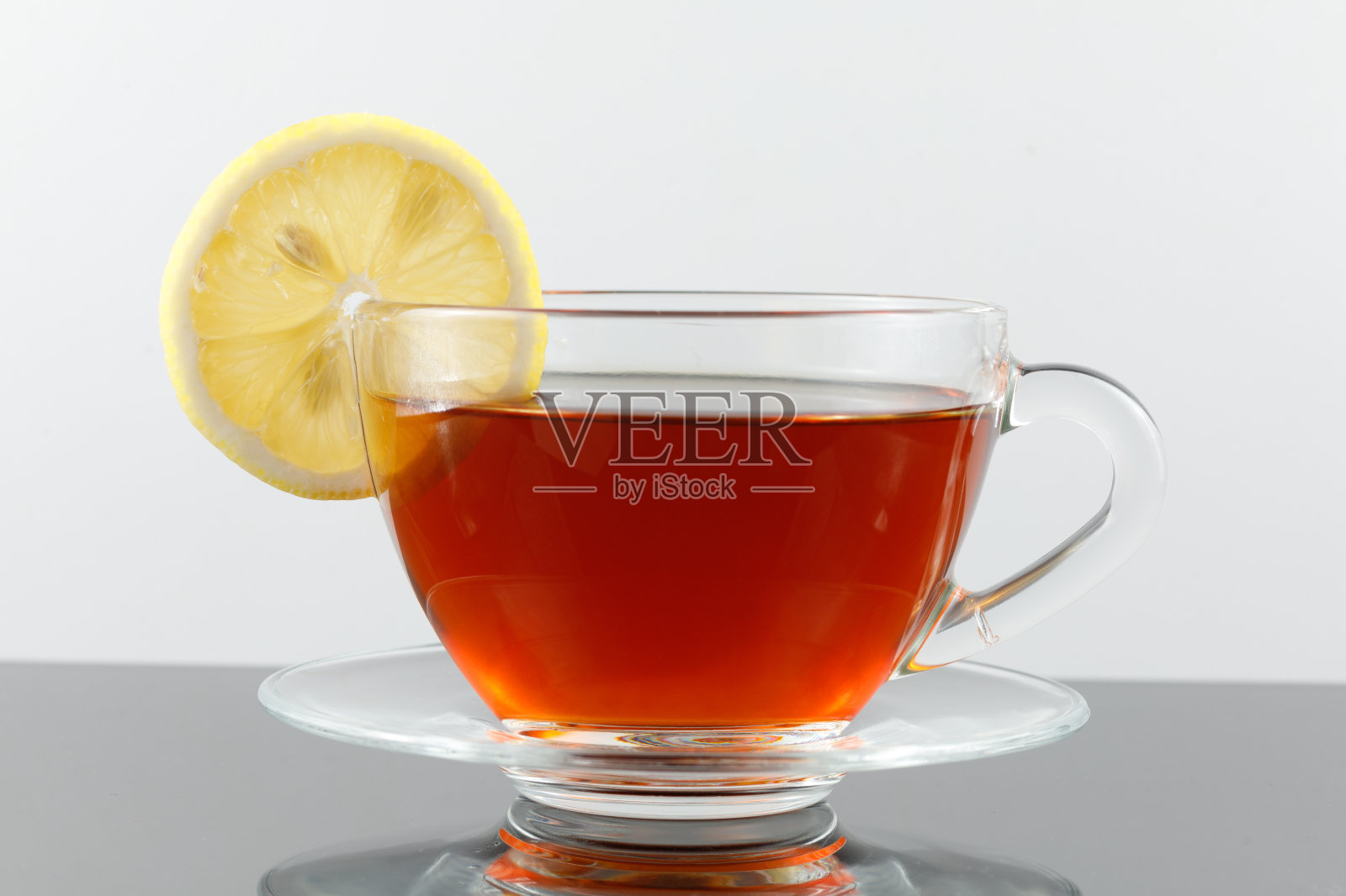 一杯加柠檬的茶。一杯红茶加一片柠檬,装在玻璃杯里照片摄影图片