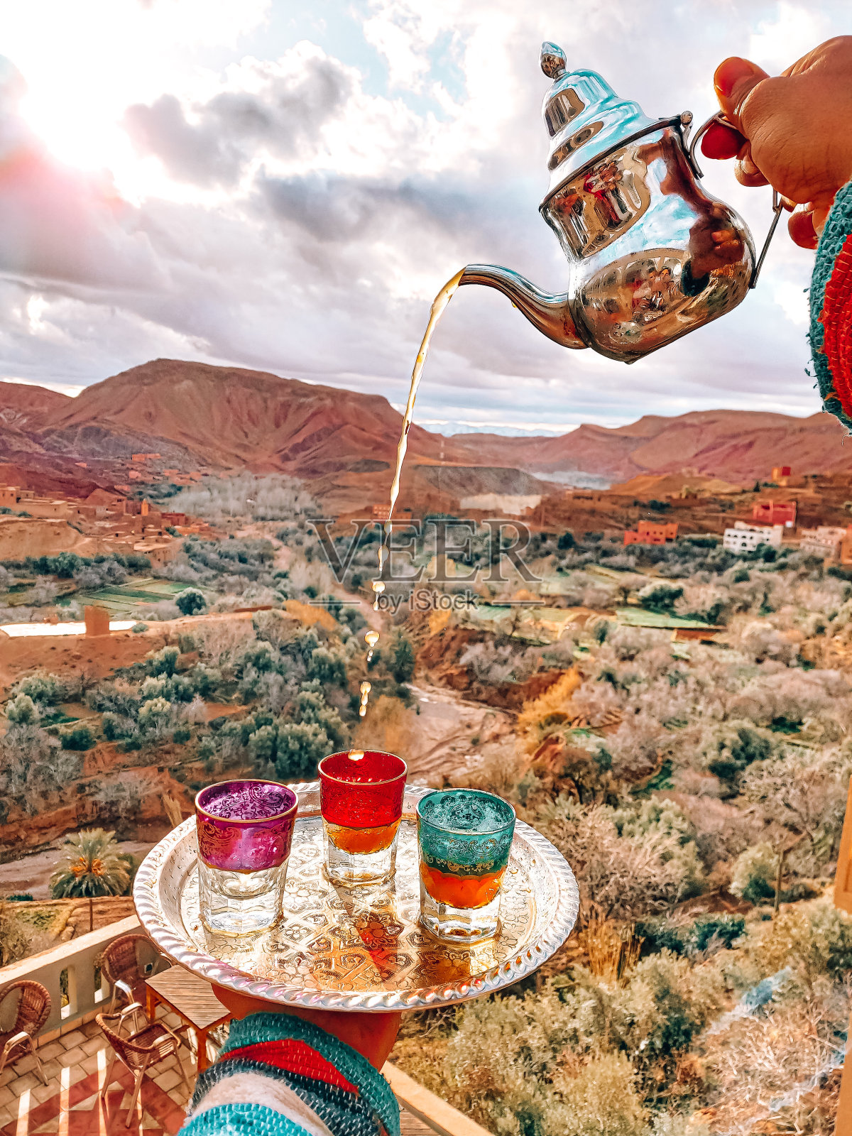 在摩洛哥Dades峡谷背景的斋月茶时间里,手把茶倒进玻璃杯里照片摄影图片