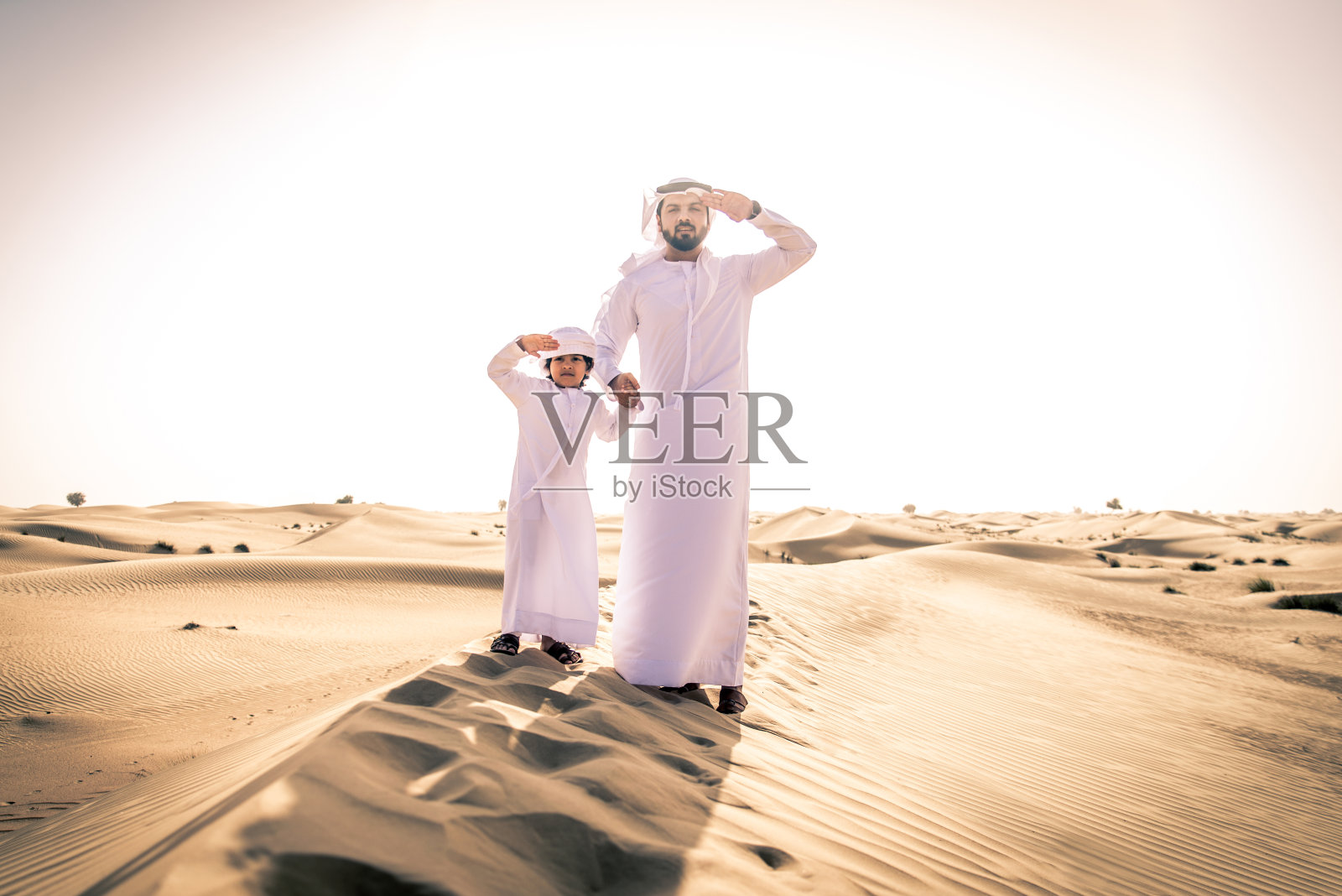 阿拉伯男子和儿子在沙漠中玩耍照片摄影图片