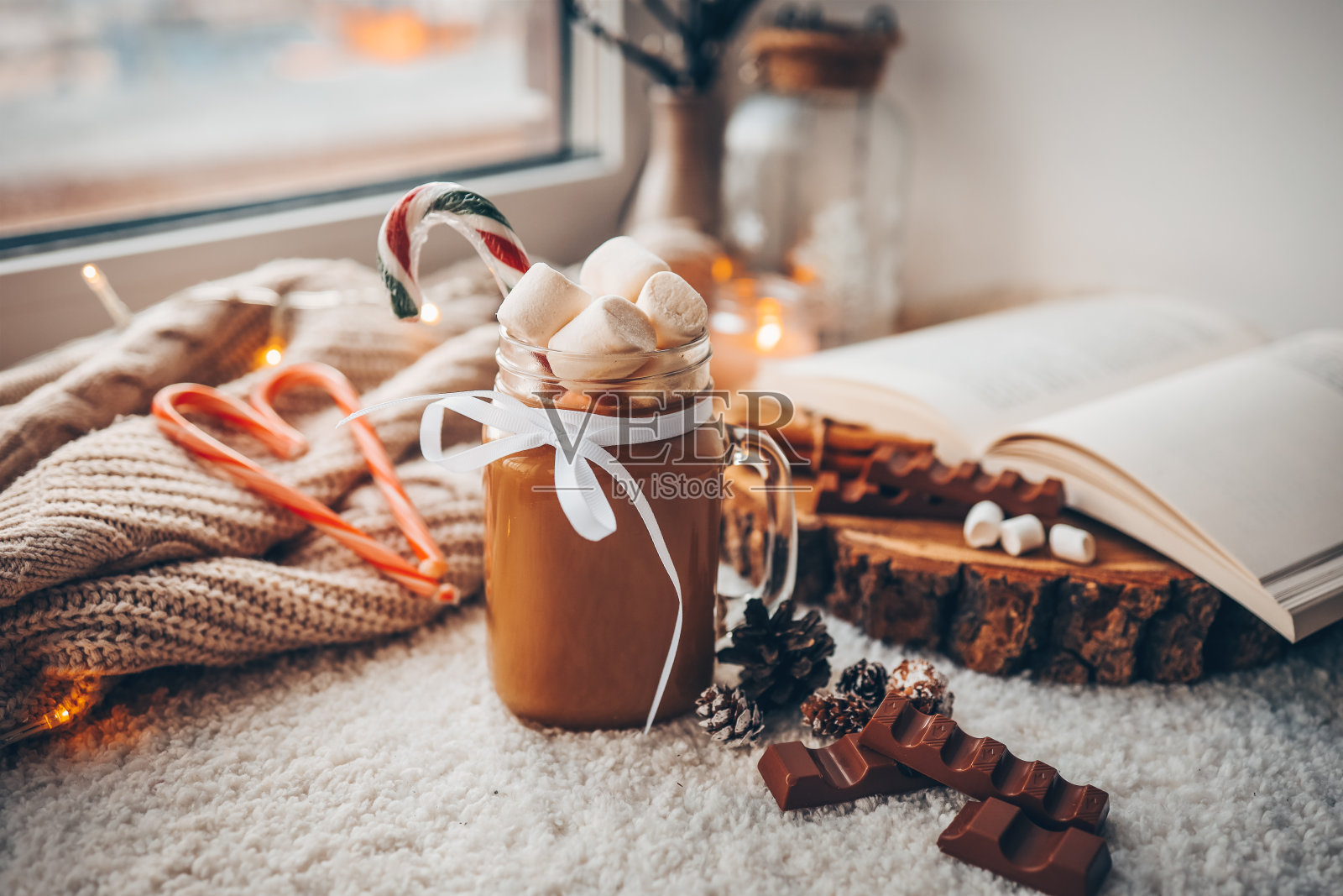 一杯有棉花糖的可可,巧克力,一本打开的书,在舒适的家庭气氛的窗台上的灯。圣诞节的美学照片摄影图片