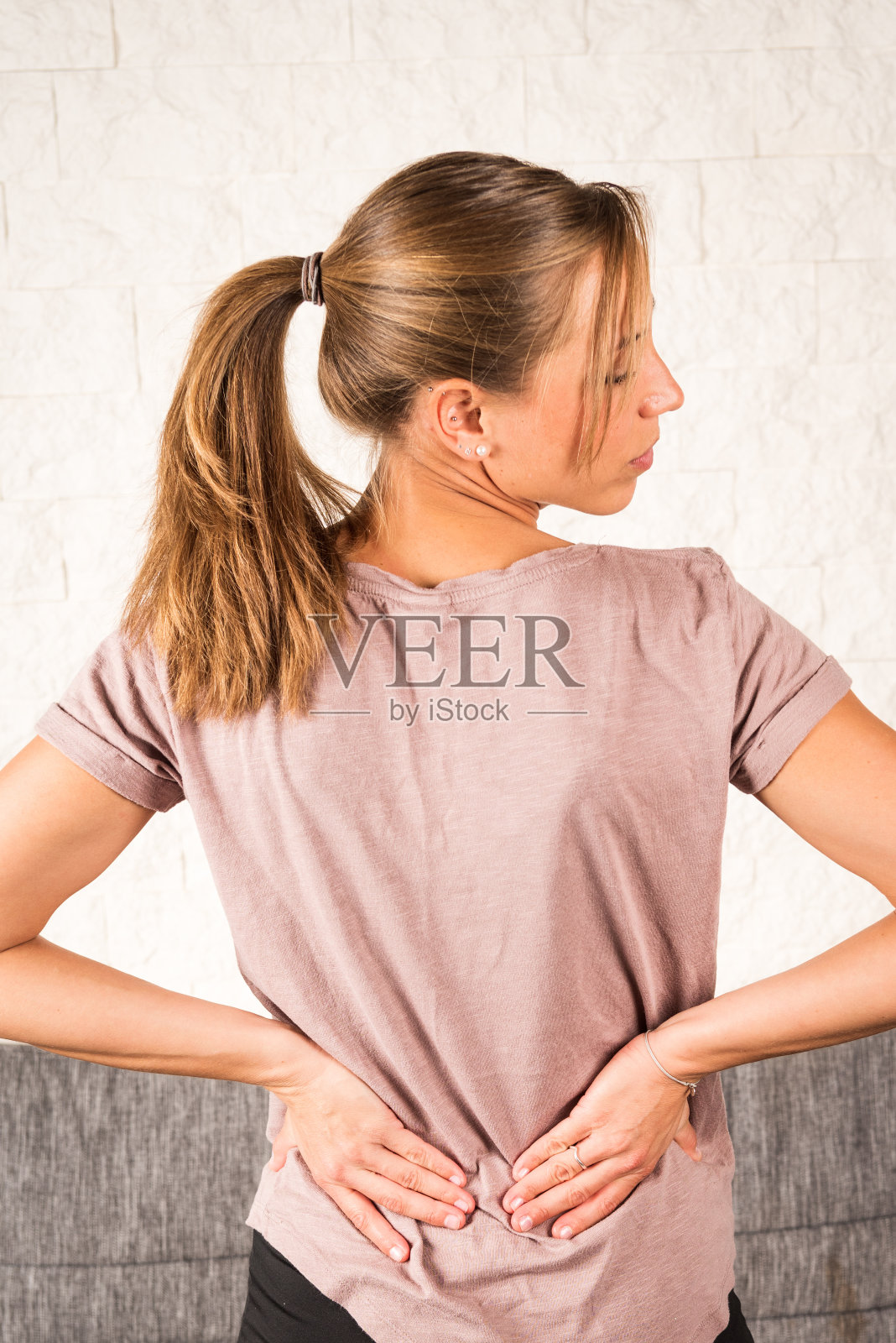 腰痛;金发欧洲女人,手放在她的背上照片摄影图片