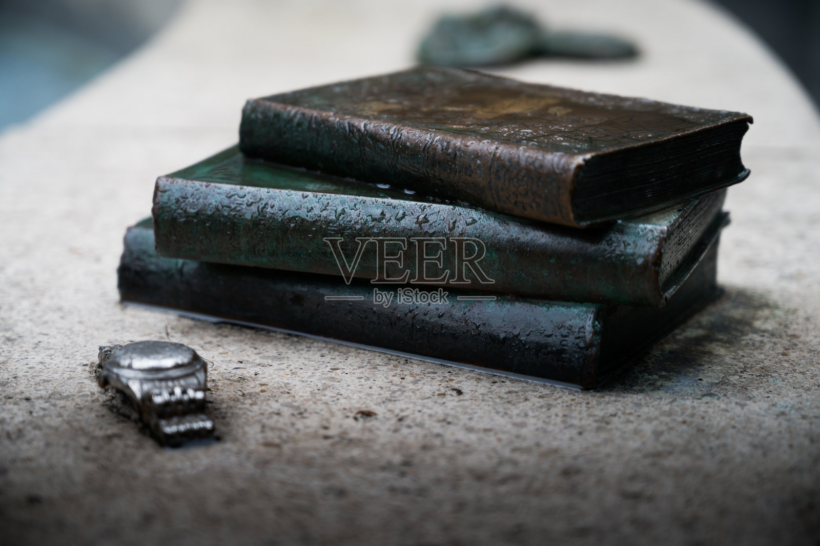三本老书,上面有雨滴,一块银手表放在石凳上照片摄影图片