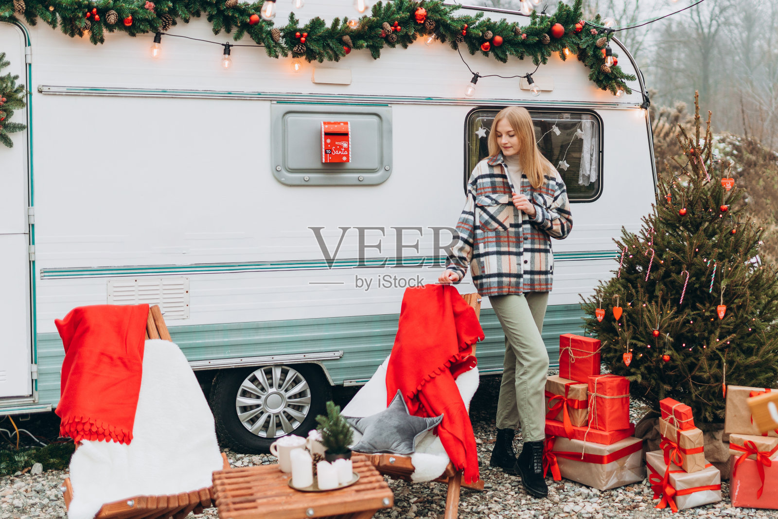 快乐的年轻女子站在现代房车附近的户外。新年和圣诞节的概念。照片摄影图片