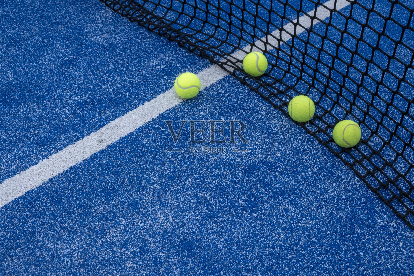 选择性聚焦,四个球在球拍网球场的网前。球拍运动照片摄影图片