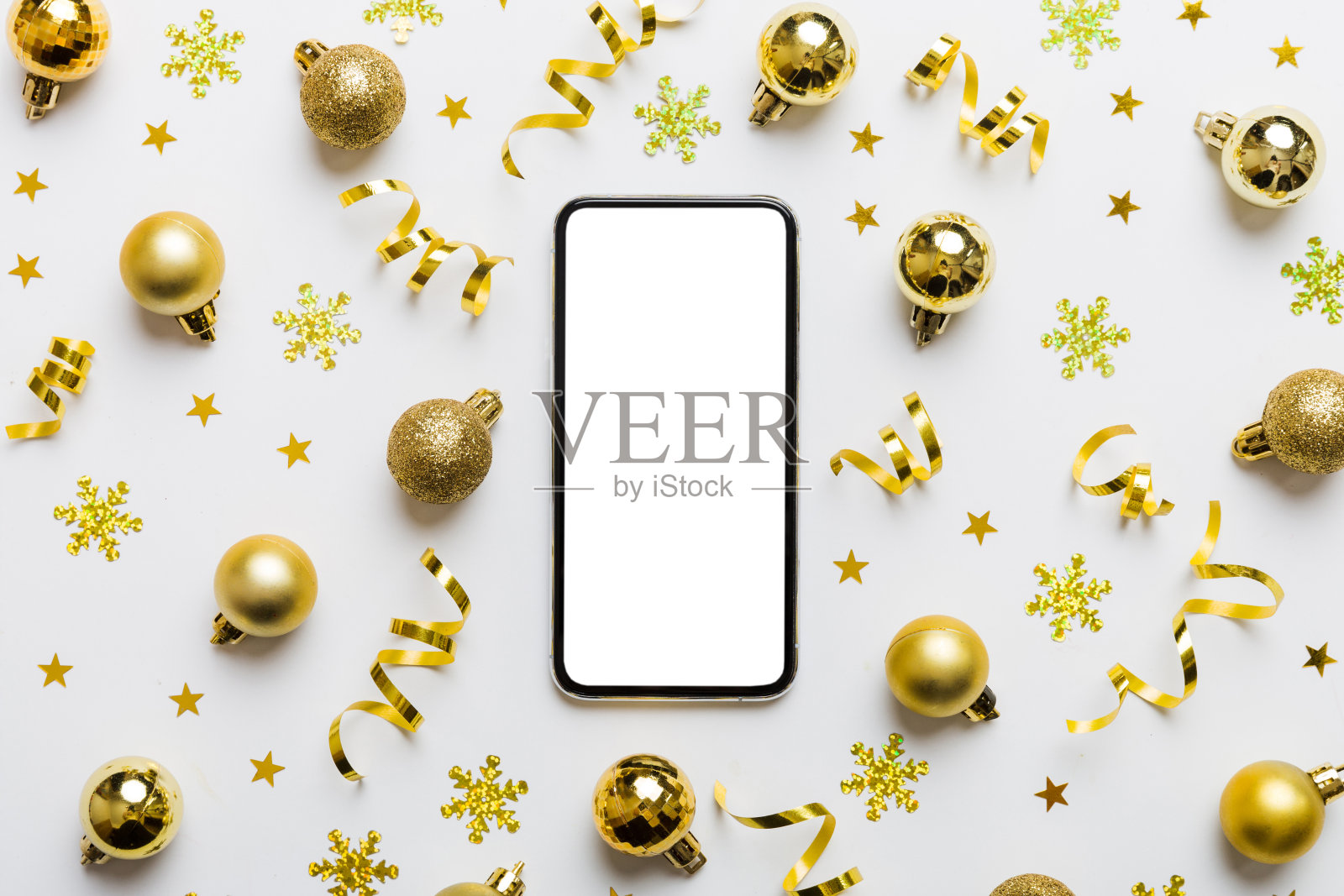 在家用手机进行圣诞节线上购物,顶部显示空白白色屏幕,智能手机在彩色背景上带有圣诞装饰球和复制空间,冬季假日促销背景照片摄影图片