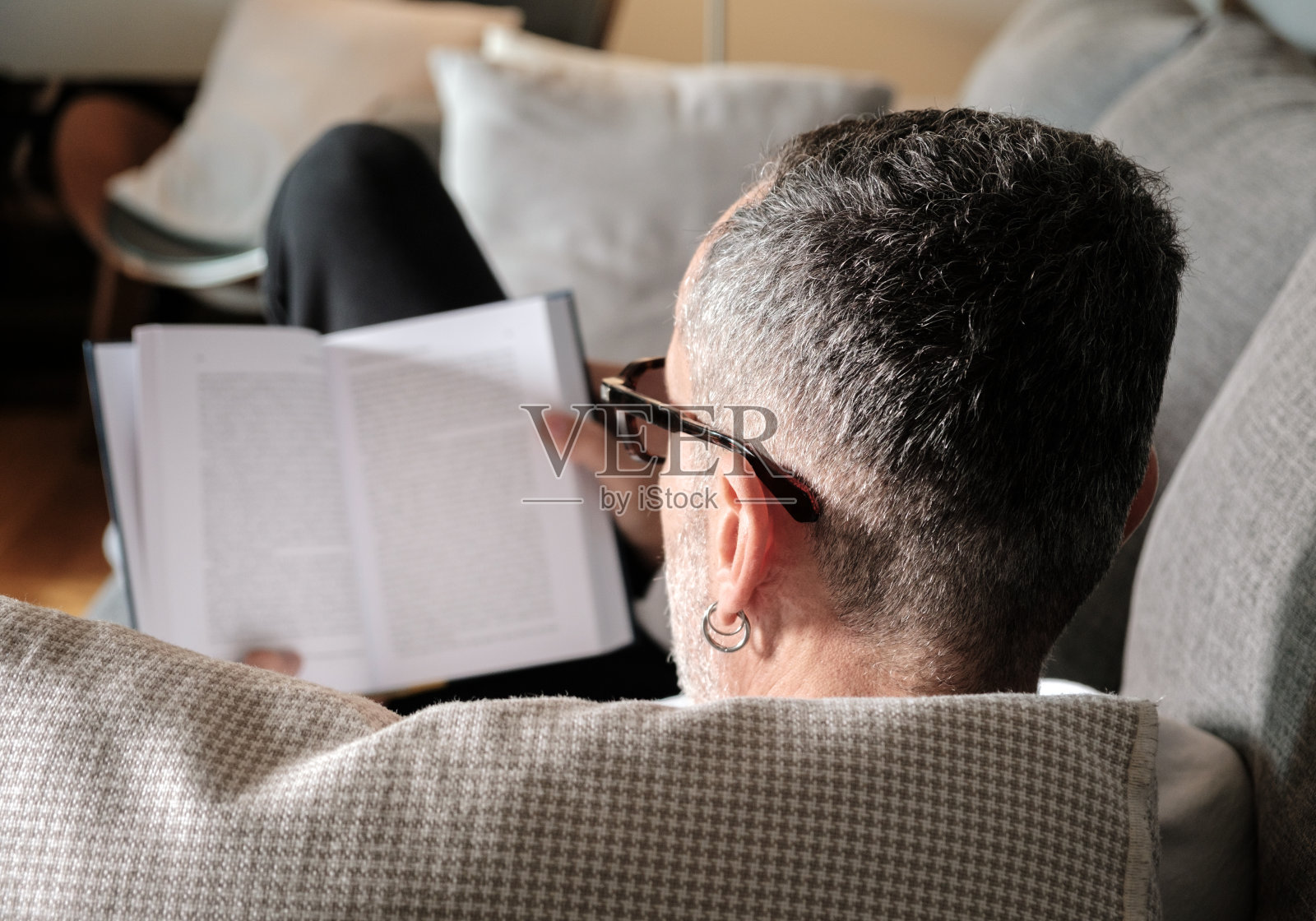 男人在沙发上看书。照片摄影图片