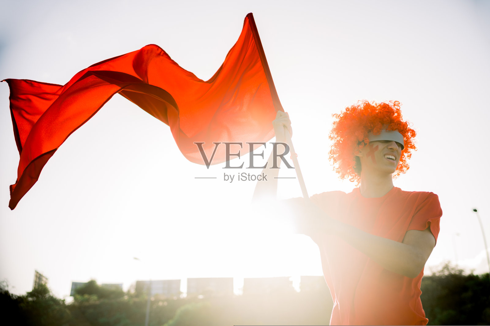 年轻的民族男子戴着VR眼镜在街上挥舞旗帜照片摄影图片