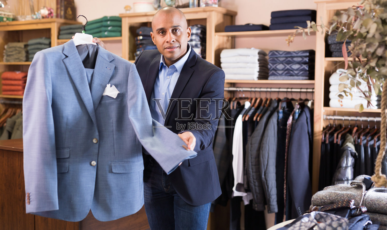 友好的推销员在男装精品店提供西装照片摄影图片