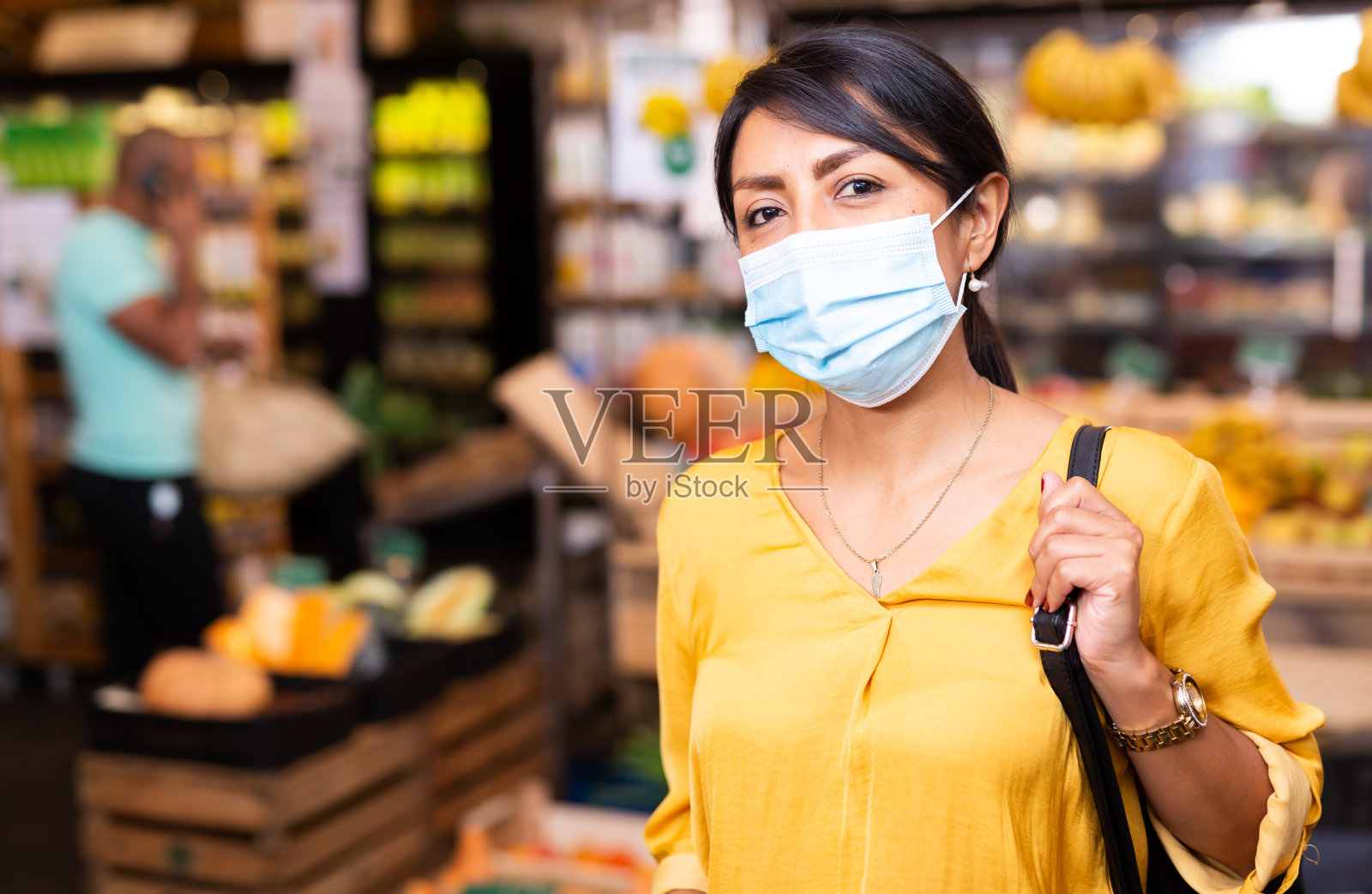 戴着防护口罩的妇女在商店拿着蔬菜包和篮子照片摄影图片