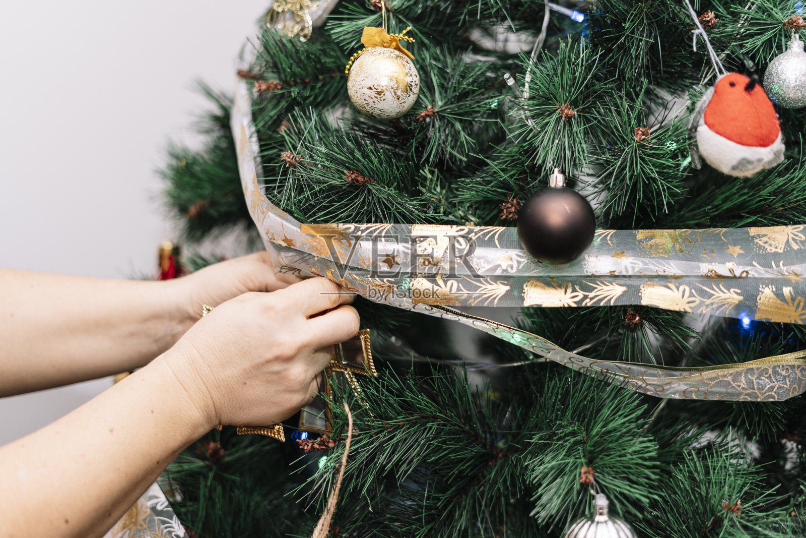 一名妇女正在用手装饰圣诞树,以改善她自己房间的室内气氛。照片摄影图片