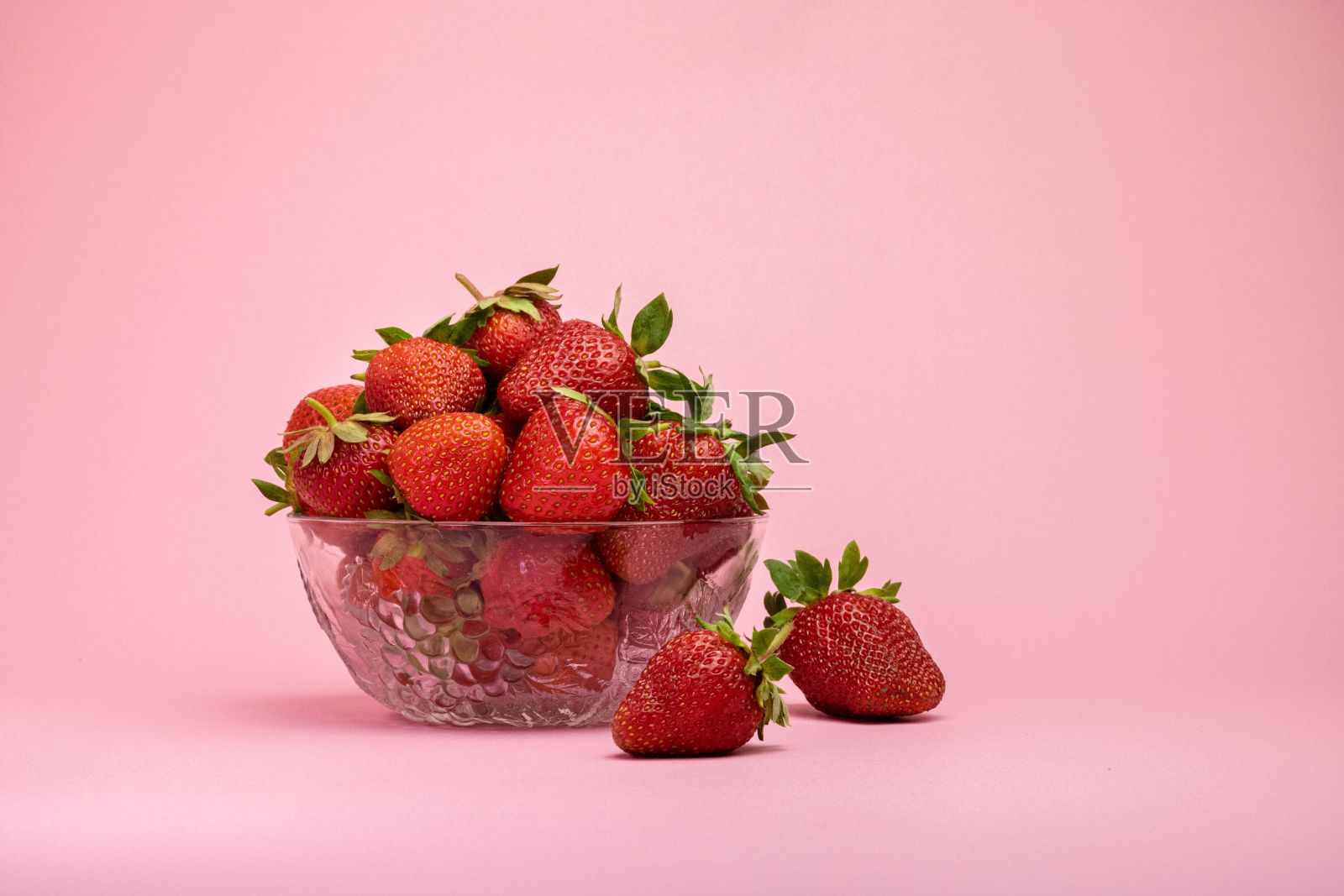一碗美味多汁的草莓在粉红色的背景照片摄影图片