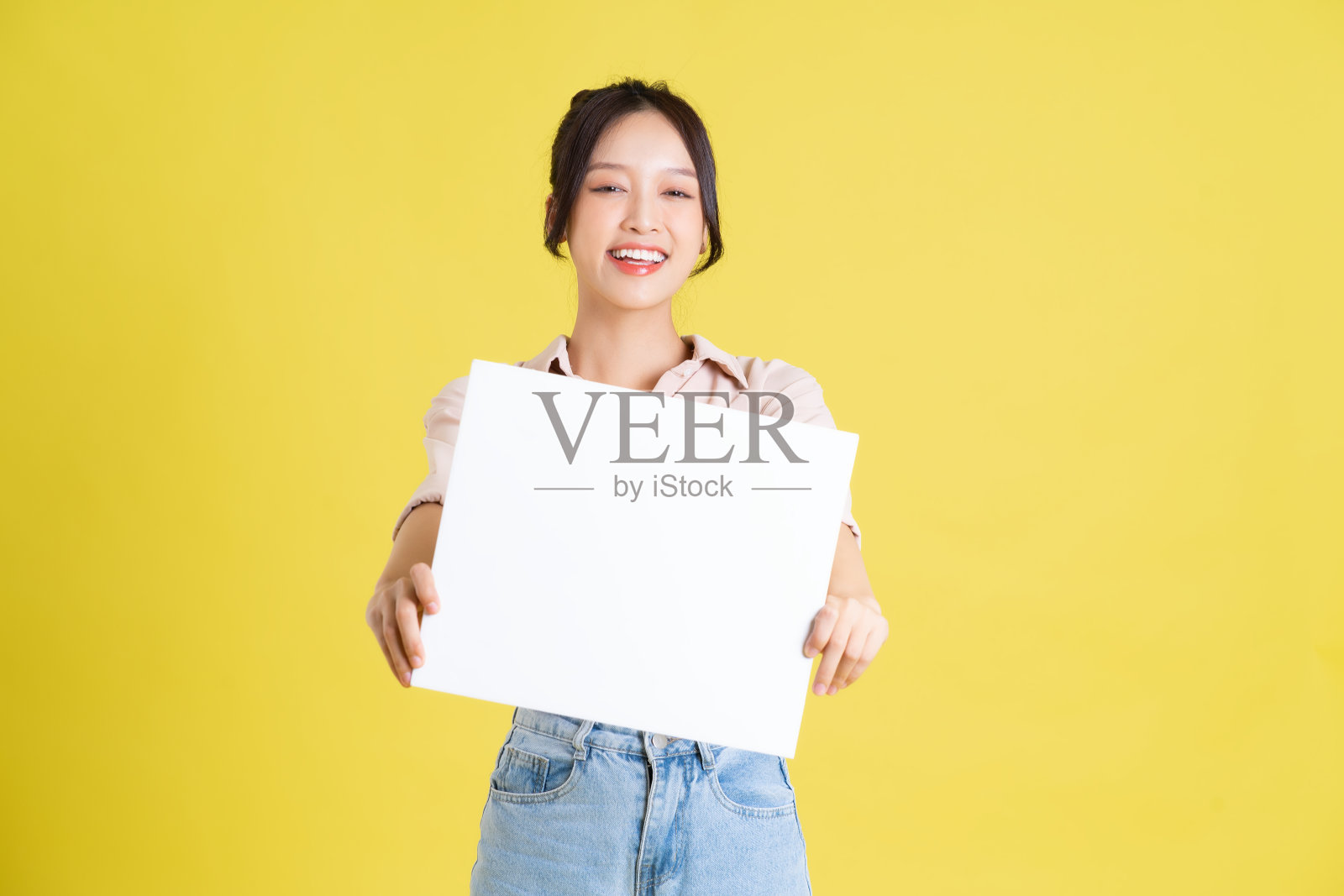 一个漂亮的亚洲女孩举着一个白色广告牌的形象照片摄影图片