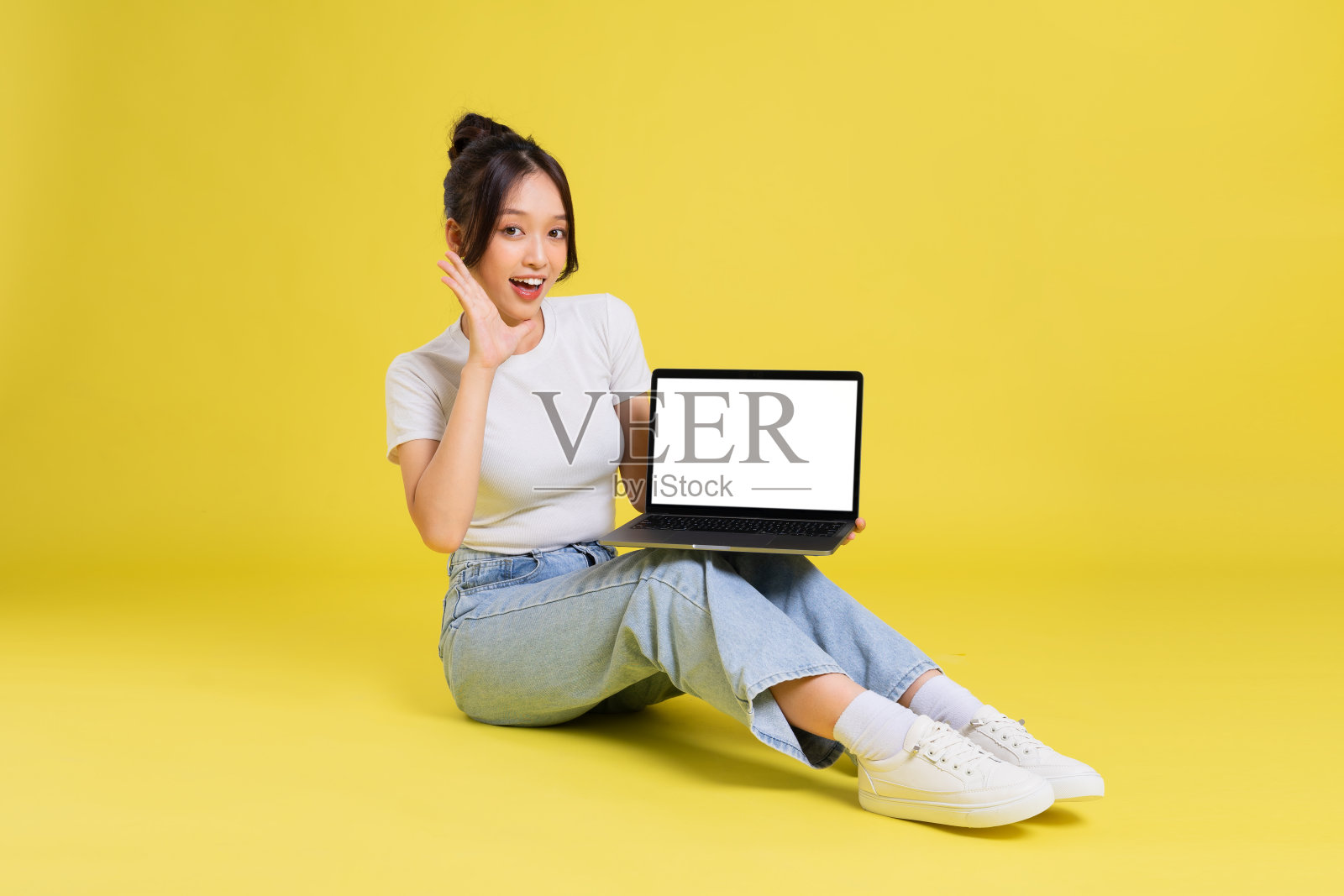 一个美丽的年轻亚洲女孩坐在黄色背景的肖像照片摄影图片