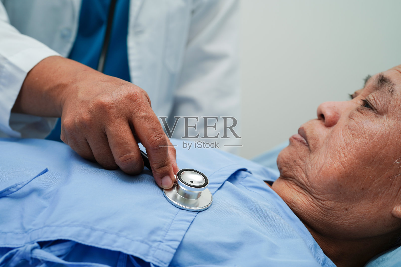 医生在门诊医院照顾、帮助和鼓励亚裔老年女性患者。照片摄影图片