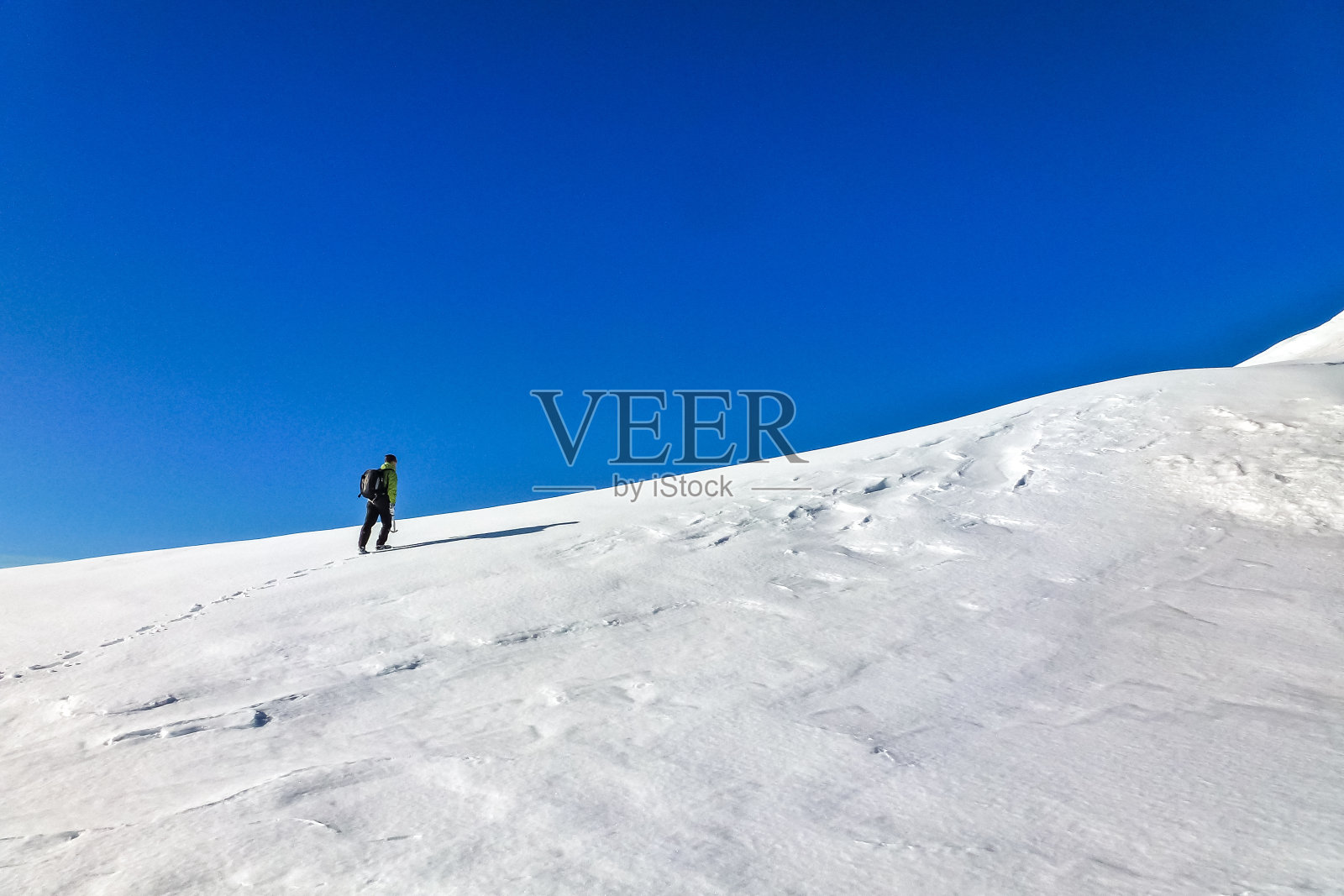 Enthusiastic mountaineer hiking on huge snow field on Jungfrau. Jungfrau-Höhenweg, Bernese Alps, Switzerland, Europe.照片摄影图片
