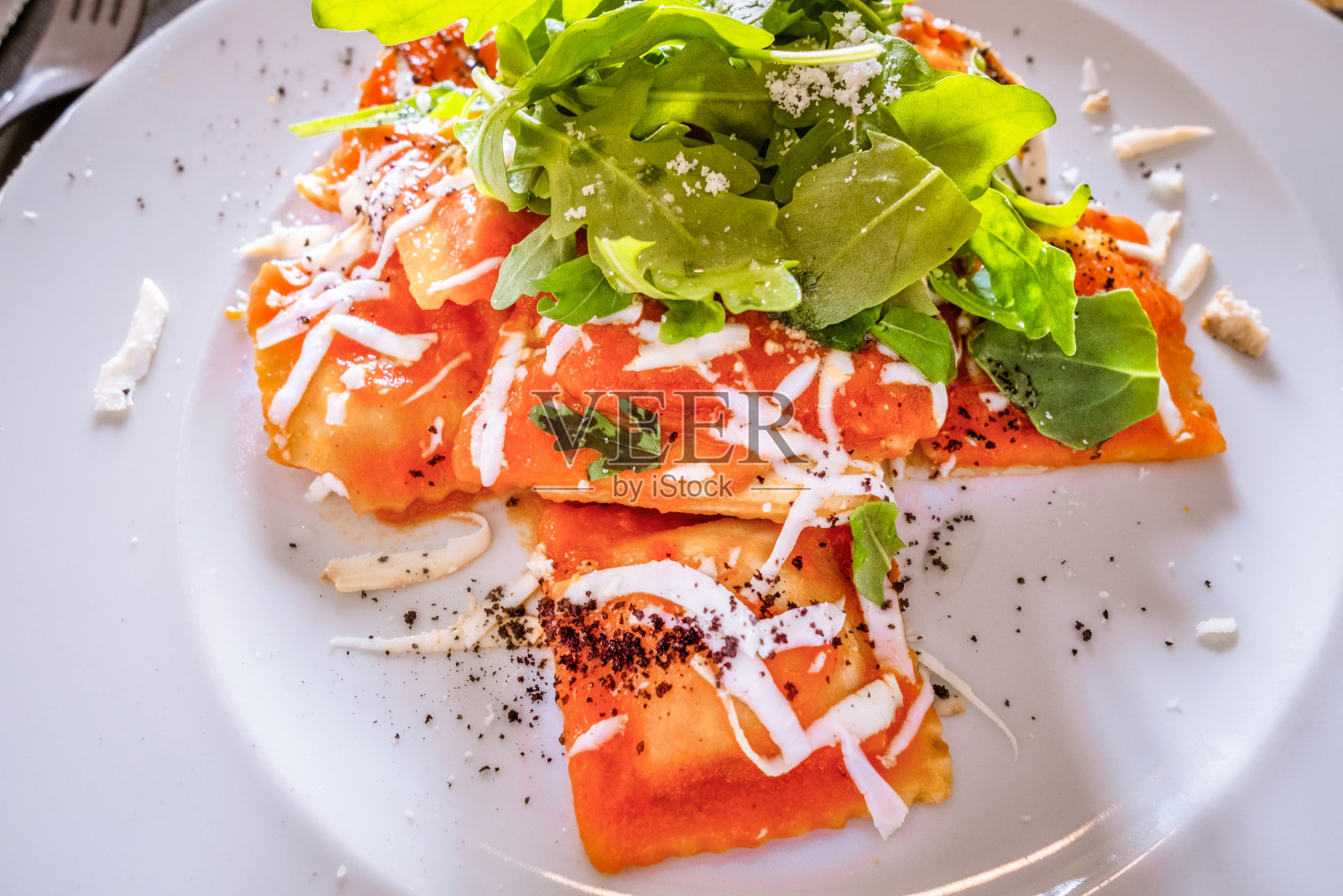 美味的意大利饺子,番茄酱,芝麻菜,莫扎里拉奶酪和黑松露刨花,放在白色的陶瓷盘子里。照片摄影图片