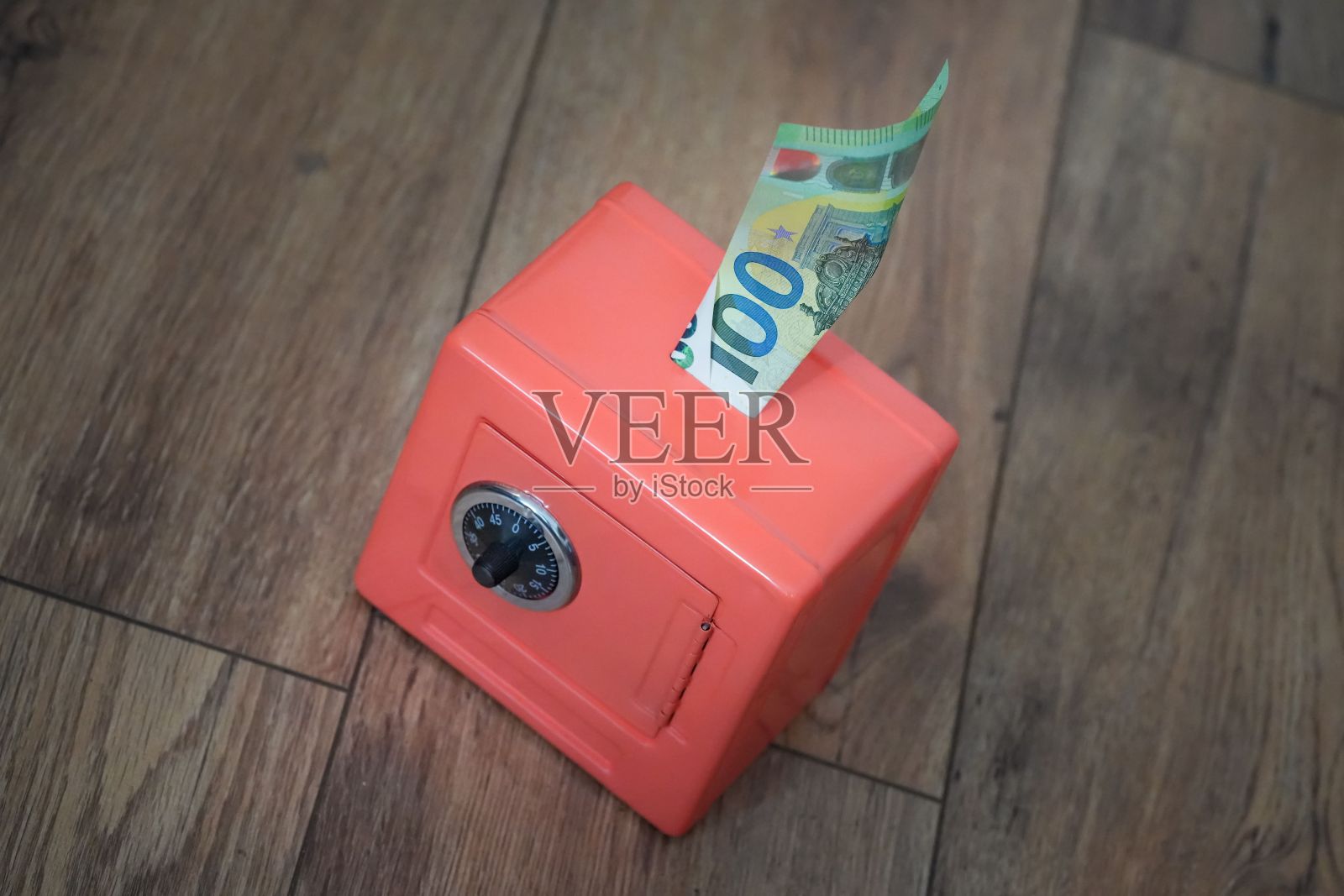 一张100欧元钞票的特写,从一个小的红色保险箱里伸出来,放在一所房子的木地板上照片摄影图片