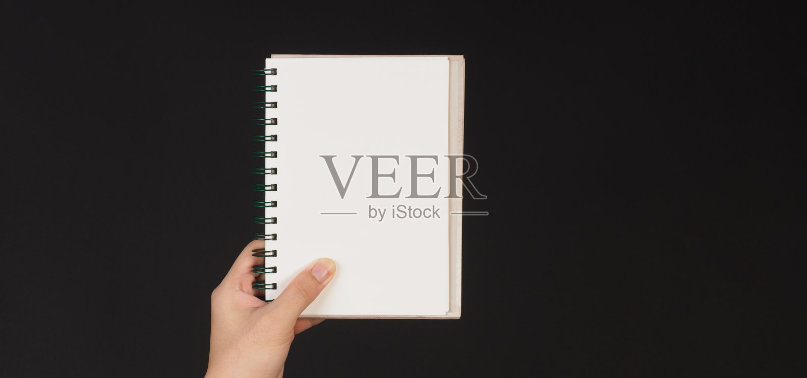 手在黑色背景上单独拿着笔记本照片摄影图片