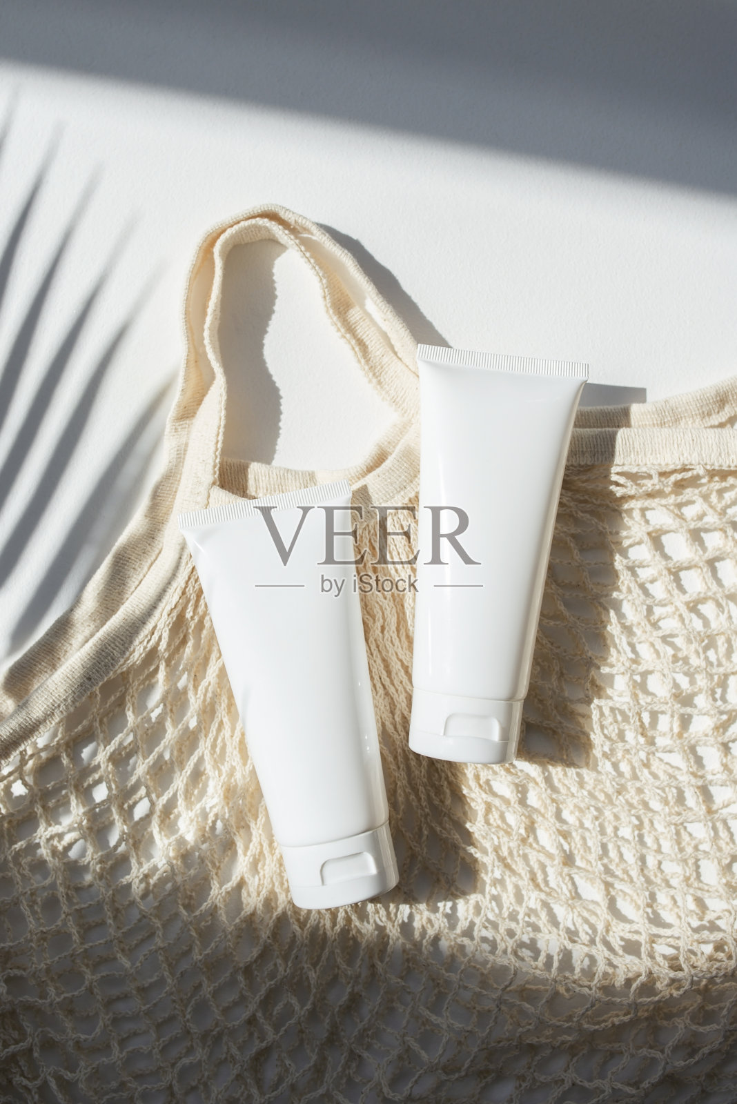 白色塑料管装面霜或乳液,布质购物袋。照片摄影图片