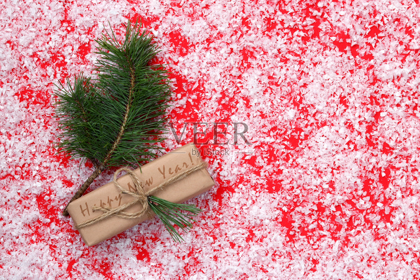 一棵云杉树枝旁的新年礼物,红色背景上的一幅作品照片摄影图片