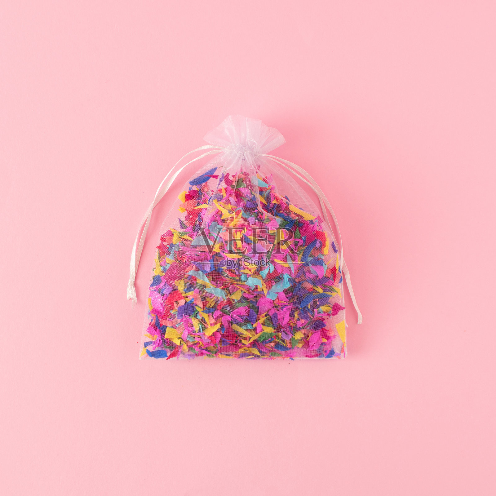 白色礼品袋与彩色纸屑粉红色粉彩的背景。最小的庆祝概念。照片摄影图片