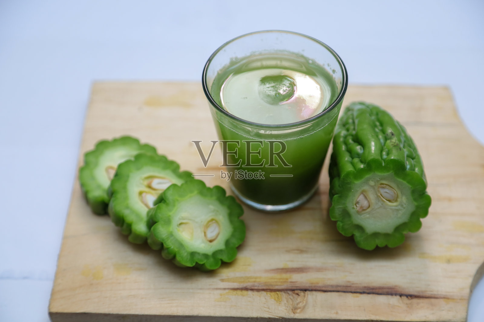 苦瓜和苦瓜汁放在木板上。苦瓜汁是一种治疗糖尿病的草药照片摄影图片