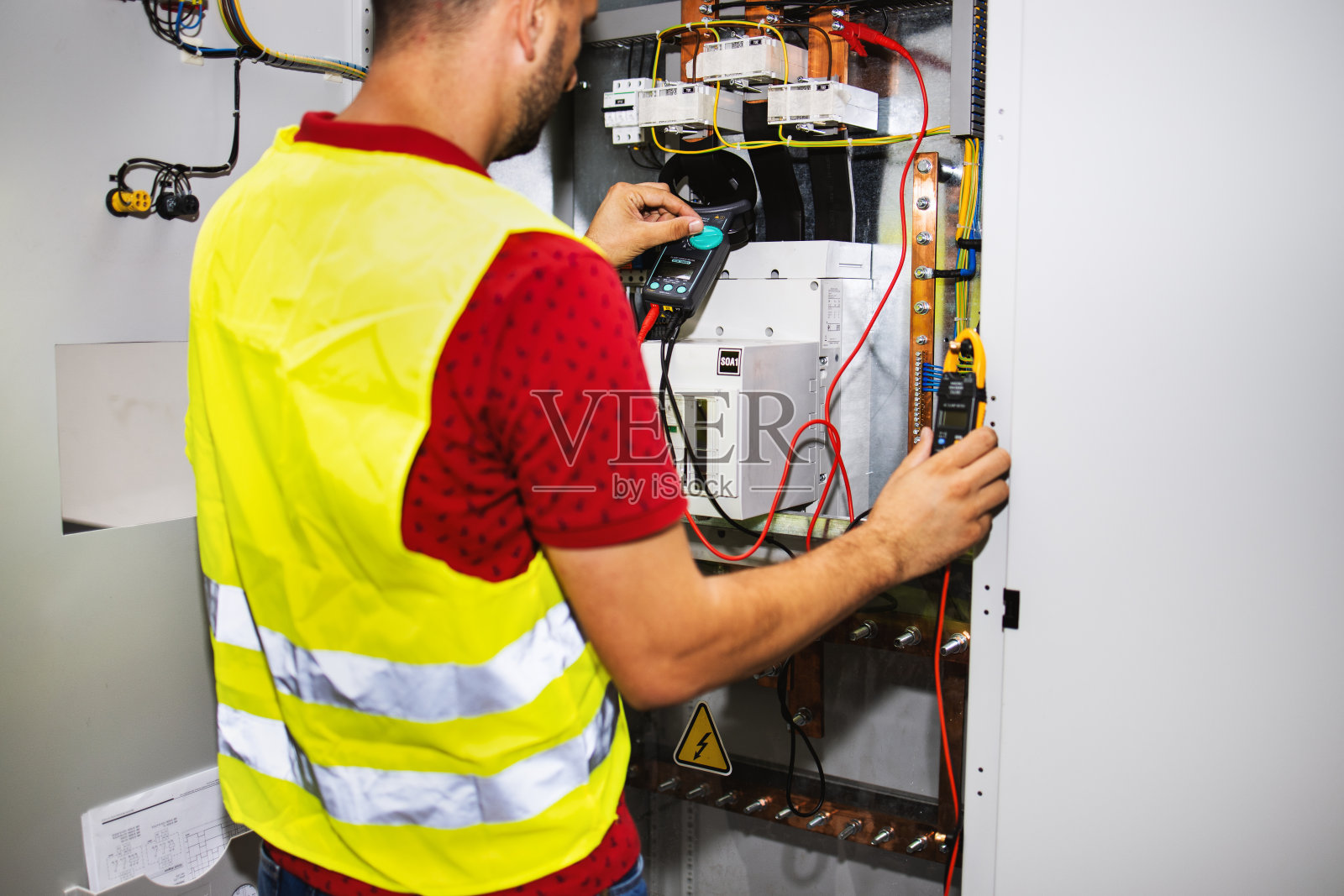 电工工程师工作测试仪测量电控箱中电力线路的电压和电流。照片摄影图片