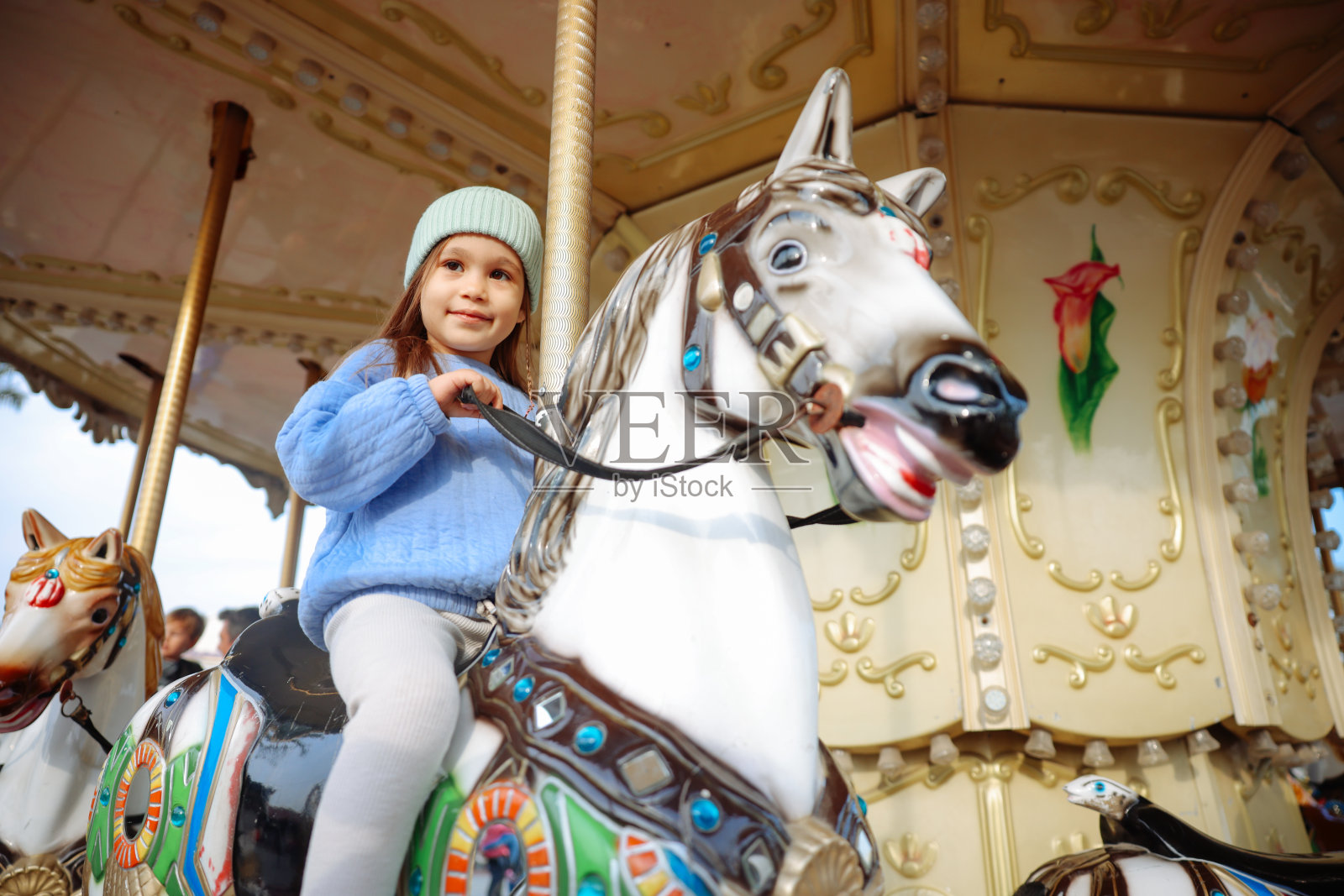 骑着旋转木马的漂亮孩子。可爱的女孩是骑吸引力。有趣的庆祝活动照片摄影图片