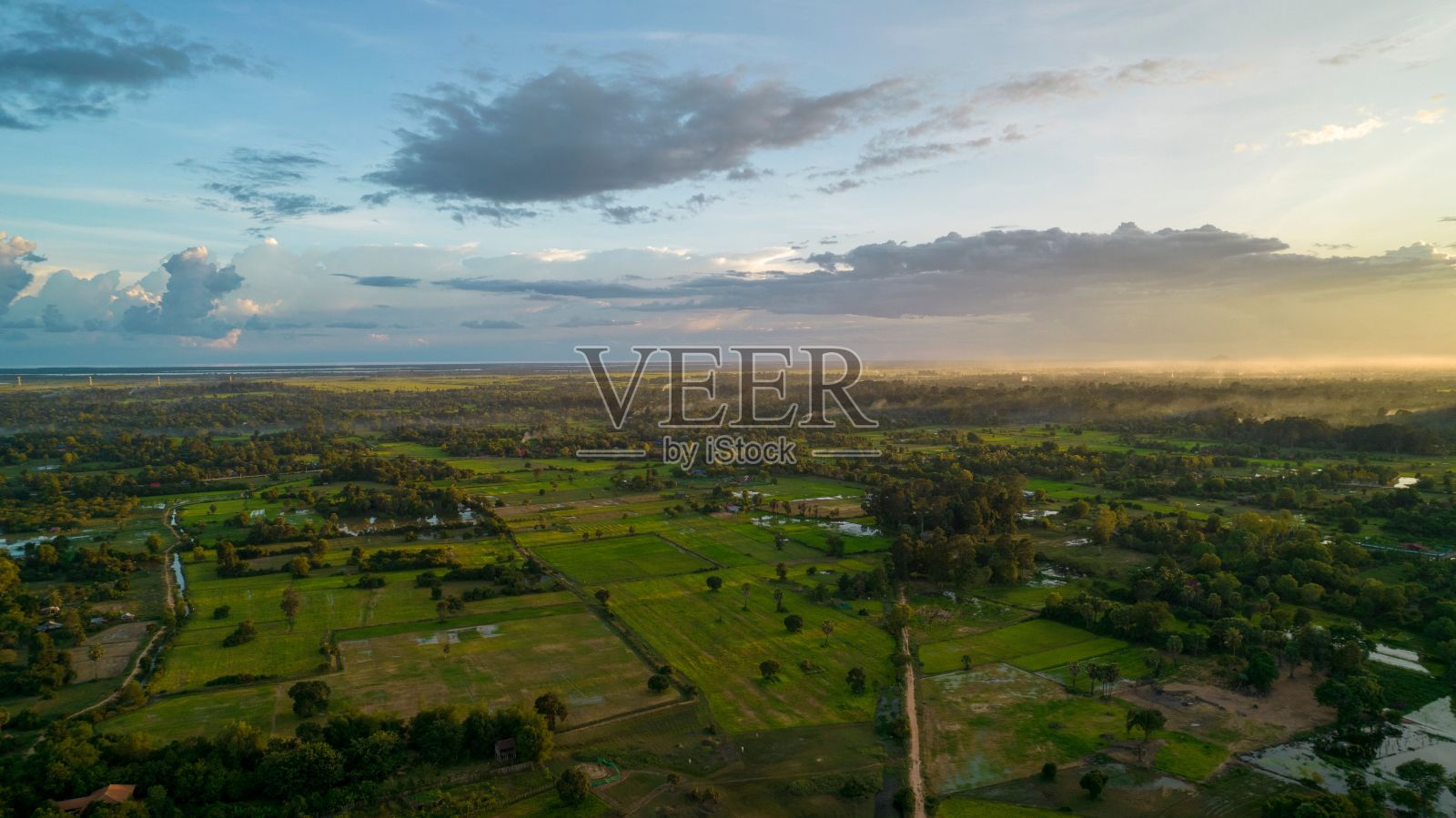 无人机拍摄的农村居民区与绿色植被和农田在日落照片摄影图片